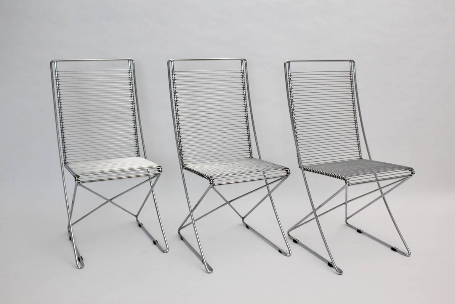 Postmoderne Vintage-Stühle, 3er-Set, aus verchromtem Stahldraht in skulpturaler Form, Modell Kreuzschwinger.
Die Esszimmerstühle wurden von Till Behrens 1983 Deutschland entworfen und von Schlubach, Grieben Brandenburg Deutschland hergestellt.
alle