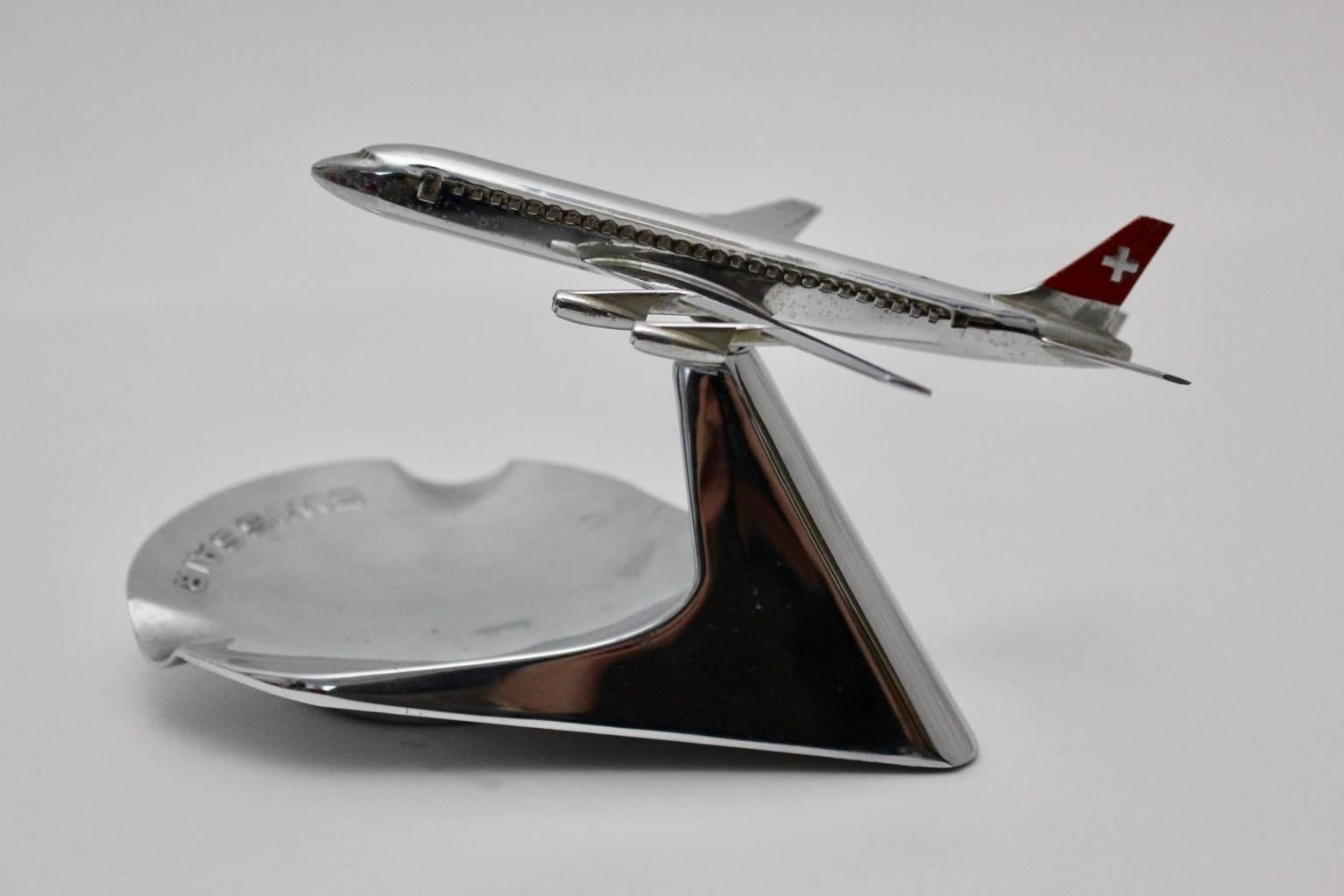 This ashtray is combined with an sculpture from an airplane from Swissair, circa 1960.
 It was made of chromed metal and it is stamped underneath, Bühler 6491, made in Switzerland.

The condition is very good with nice fine scratches.