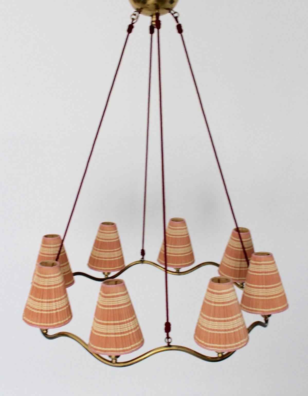 An Art Deco Era chandelier attributed to Hugo Gorge Austria 1930s, which shows a beautiful wave shape.
Eight sockets E 27  with eight lamp shades made of plastic and formed with plisses striped in the colors soft pink and ivory. The original lamp