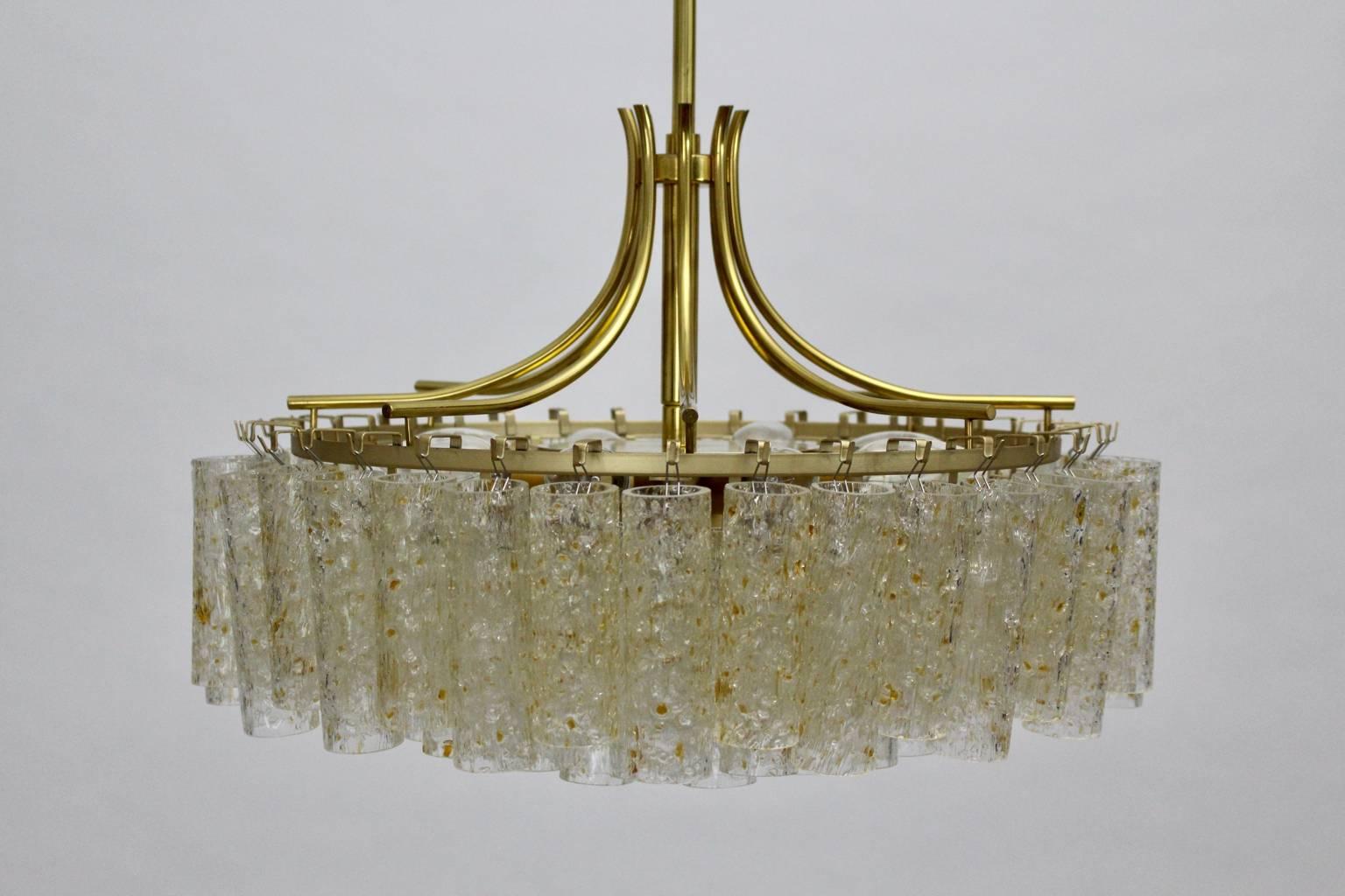 Mid Century Modern vintage chandelier from brass and textured glass rolls model 4479/8, which was executed by Doria Leuchten Germany, 1970s.
The chandelier has 4 tiers with 77 textured glass tubes and it lights with 9 sockets E 14.
The stem was made