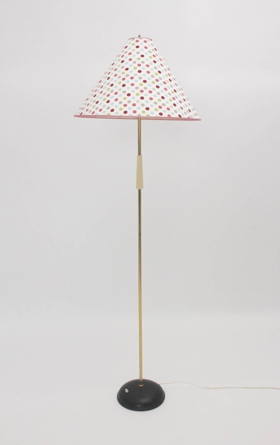Mid century modern vintage floor lamp with a round black lacquered metal foot and a brass stem partly with an ivory plastic handle.
The recovered textile fabric lamp shade has a very nice pattern with dots.
The on/off switch is integrated in the