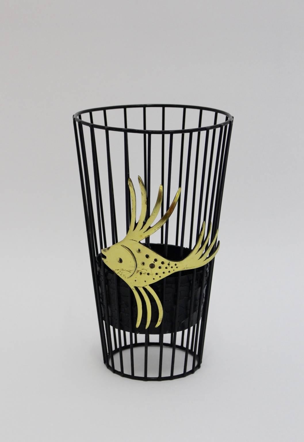 Mid Century Modern vintage black metal and brass umbrella stand was designed by Walter Bosse in Vienna.
Also the umbrella stand was made of black wire steel with drip tray inside.
A lovely brass fish decorates the umbrella stand outside.

all