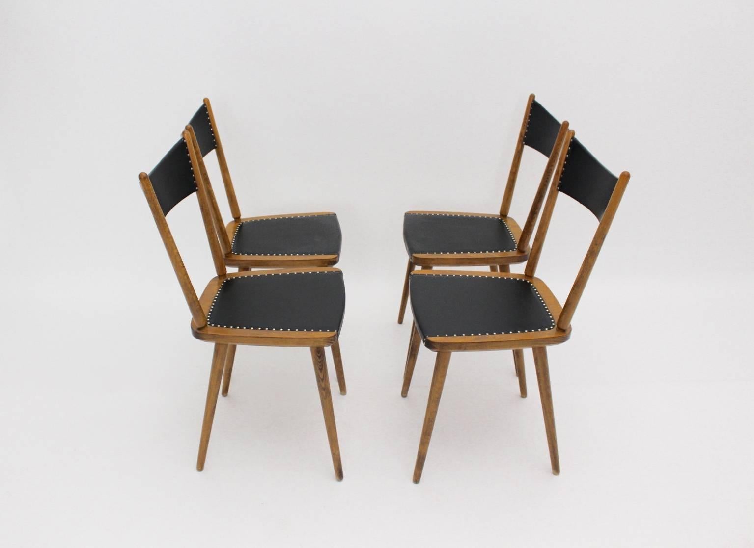 This set of four dining room chairs were made of beechwood. The seat and the back were covered with black faux leather and decorated with decorative nails.

The dining room chairs were designed and executed in Vienna, 1950s.
The condition is very