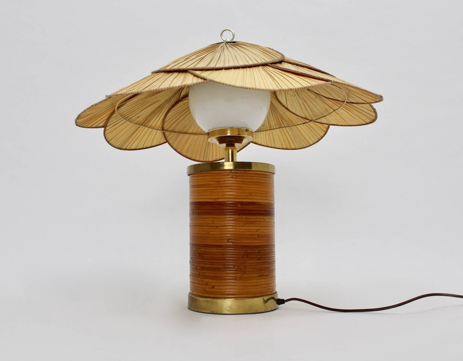 This table lamp was designed by Ingo Maurer, 1970s.
The materials are rattan, brass, an opal glass ball and exotic leaves.

The base is in very good condition with very minor signs of age.
The lampshade was made of exotic leaves, which show signs of