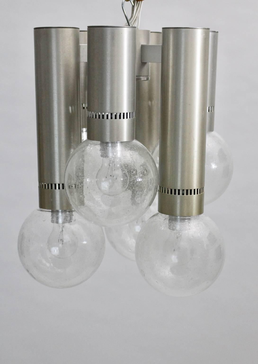 This flush mount from the space age era shows six brushed aluminium tubes and six colorless handblown glass globes with nice bubbles.
It lights with six sockets E 27.
This light will be fixed on the ceiling, but you can use this flush mount also as