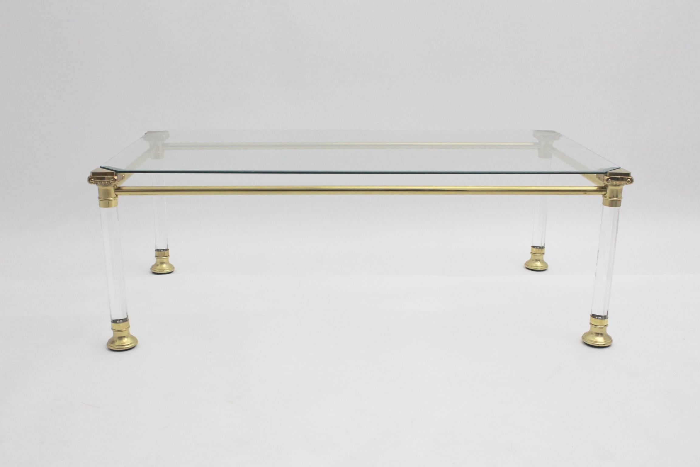 This gorgeous coffee table features four lucite feet with brass details and also a glass top.
A glass facet underlines the gracile appearance.
The condition is very good.
all measures are approximate
 
