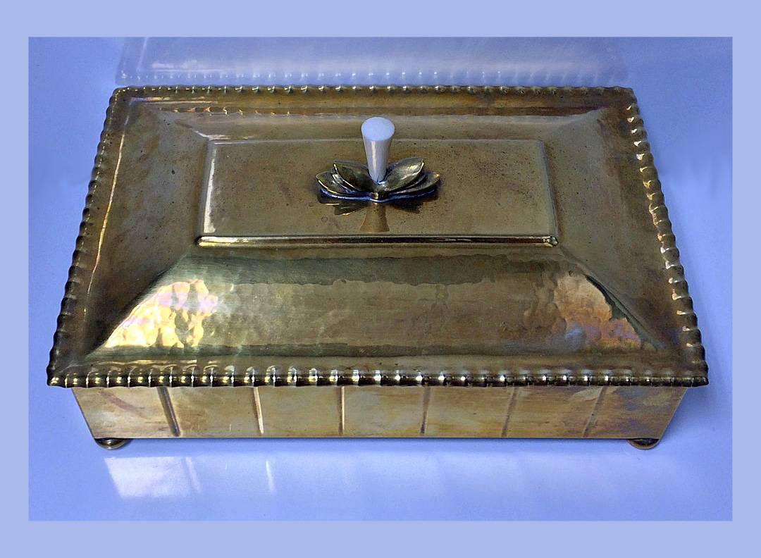 WMF Arts and Crafts hammered brass box, Germany, circa 1910. The large rectangular box on four bun supports, plain hammered body, hinged cover with crimped surround edge, stylised brass and french ivory handle. Cedar lined interior. WMF mark on