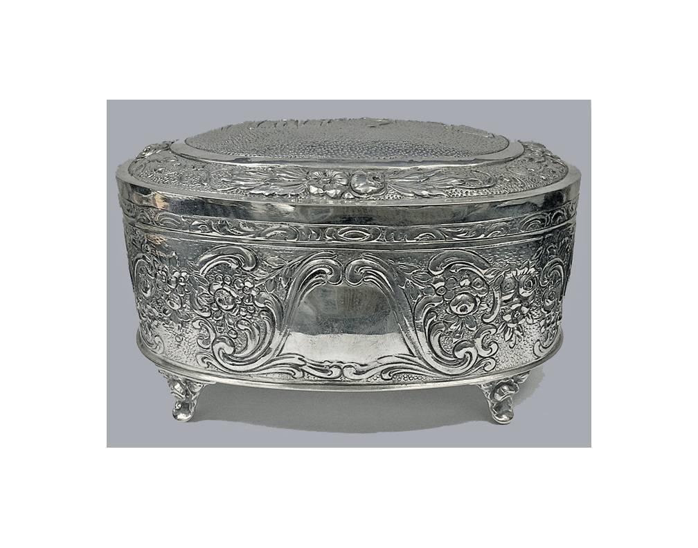 German silver Etrog box, circa 1920. Oval form with repoussé flower heads and C-scrolls throughout on a textured ground, the hinged lid with the word 