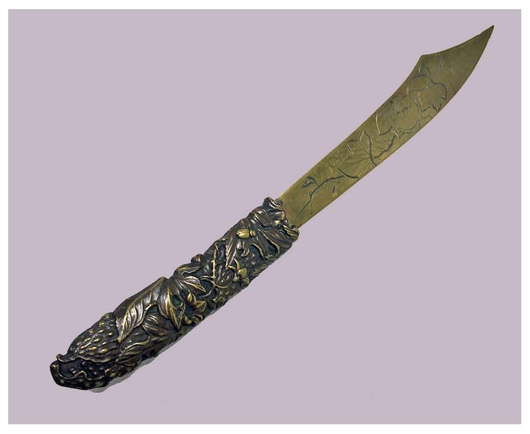 Antique 19th century mixed metals letter opener, Japanese, circa 1890. The letter opener with scimitar blade, engraved with squirrel and dragonfly amidst foliage, the handle intricate fruit and foliage interspaced with insects including bee,