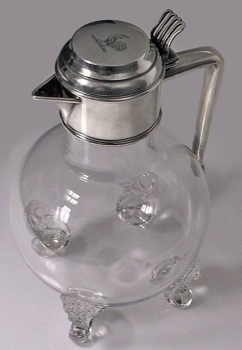 Rare antique English silver and glass whisky water jug, London 1881, Martin Goldstein. The jug of plain spherical glass bulbous form on four carved lion mask glass knuckle feet, surmounted with silver collar, handle and hinged cover, pierced linear