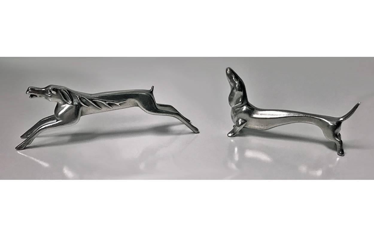 Set of six WMF knife rests, circa 1906. The polished pewter rests depict hunting theme interest and include dogs, rabbit hare and stag. All Illustrated WMF 1906 catalogue. Measures: Lengths 2.75-4.25 inches. WMF marks.