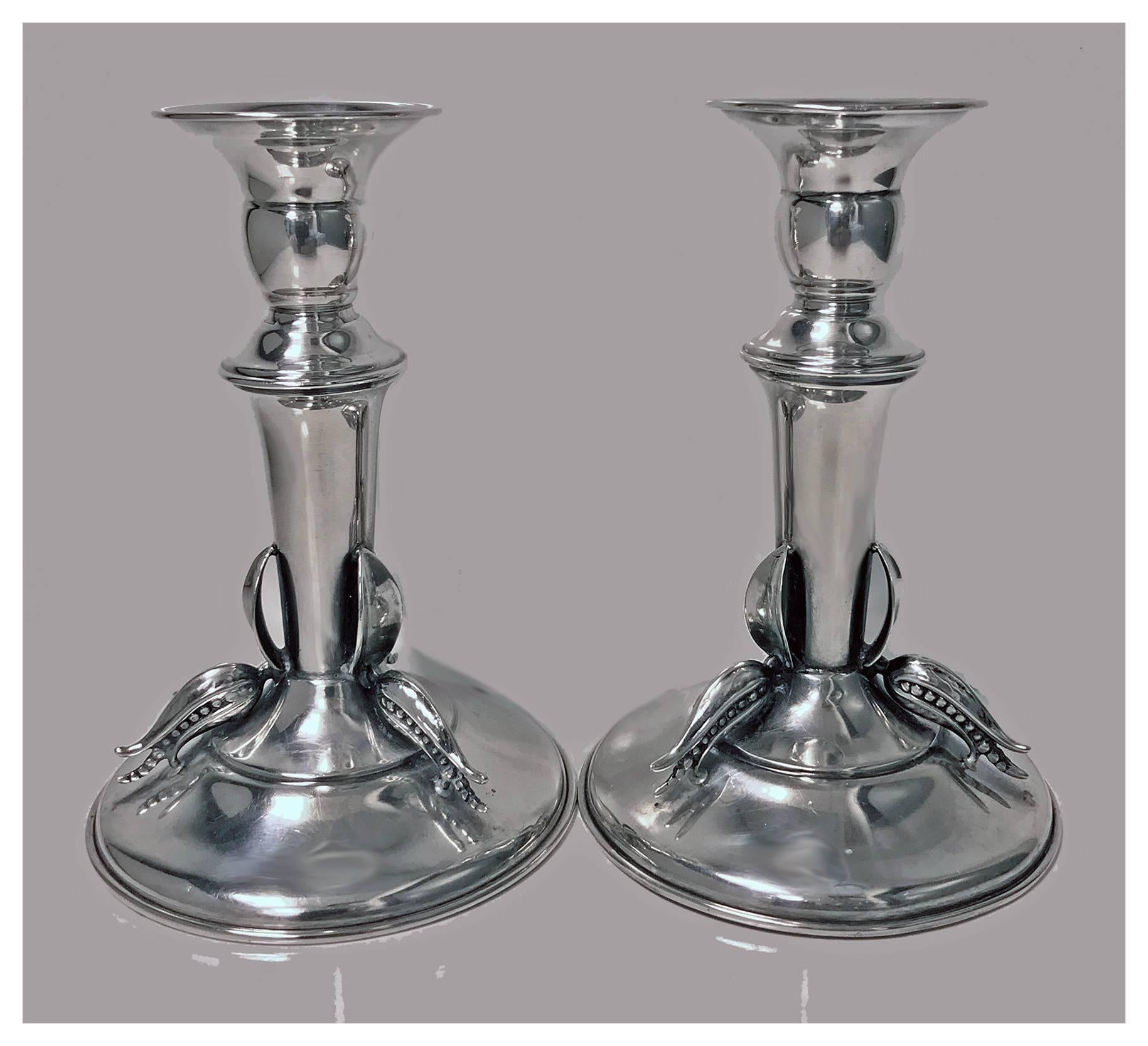 Carl Poul Petersen sterling candlesticks, Montreal, circa 1950. Each on dome base, tapered stem accented with three open bud petal surround, knopped campana sockets. Stamped on base with Petersen marks, hand made Sterling. Height: Approximately 5.4