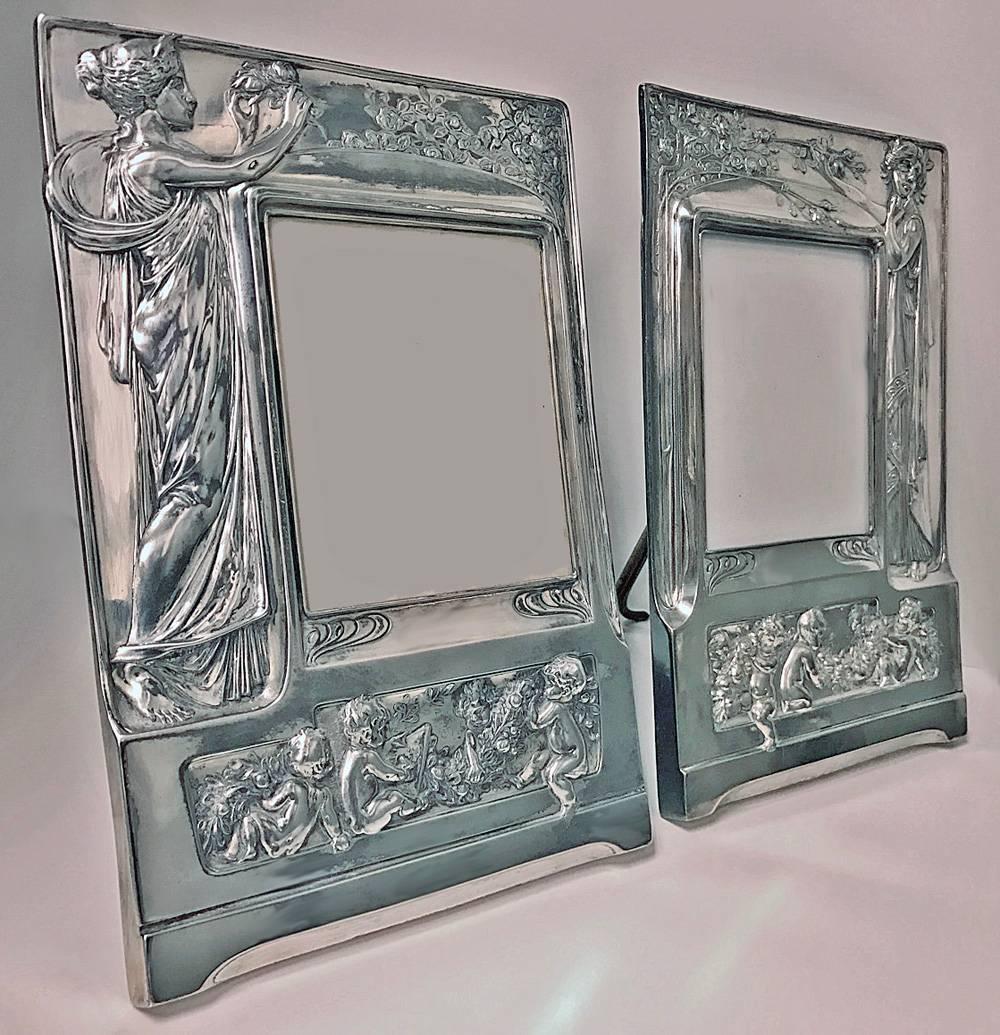 Pair of Art Nouveau large silver plate photograph frames, Germany, circa 1900. Each depicting an allegorical Art Nouveau female in long dress, grasping a foliate branch. The centres of frames vacant for photograph with a frieze of four putti amidst