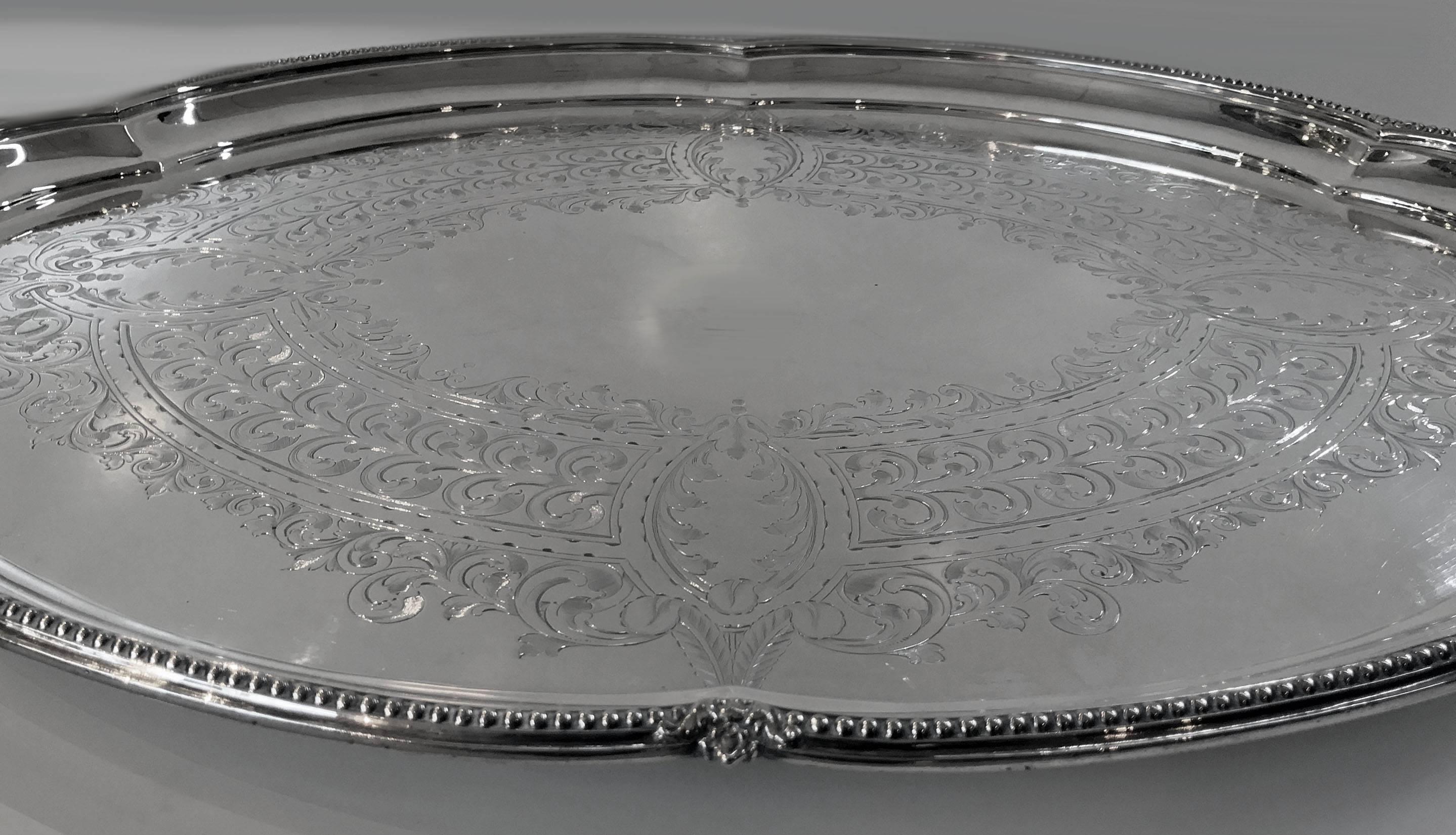Antique Victorian silver plate two handled tray, Walker and Hall, circa 1890. The large oval tray on four turned supports, raised outer bead rim and open lobate handles. The centre plain with a surrounds of engraved foliate decoration. Stamped with