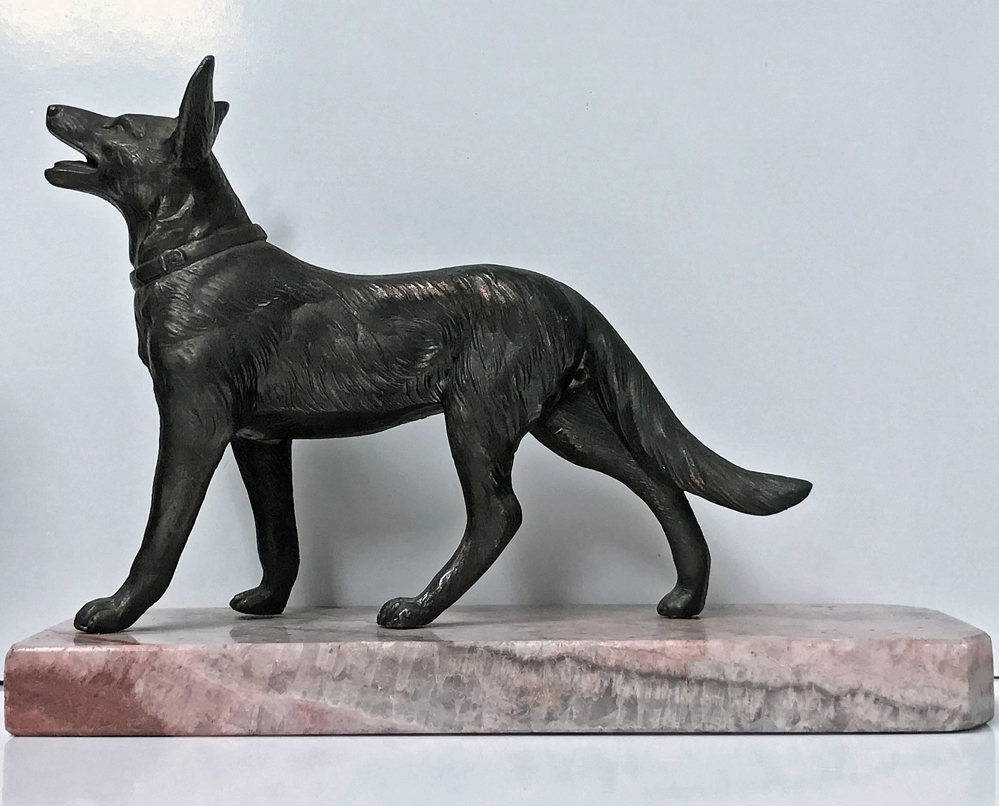 Pair of Art Deco bronze dog bookends, France, circa 1930. Each depicting an Alsatian dog on marble base. The standing Alsatian of realistic model form, textured body; surmounted on mottled light brown and cream overtone base. Each overall