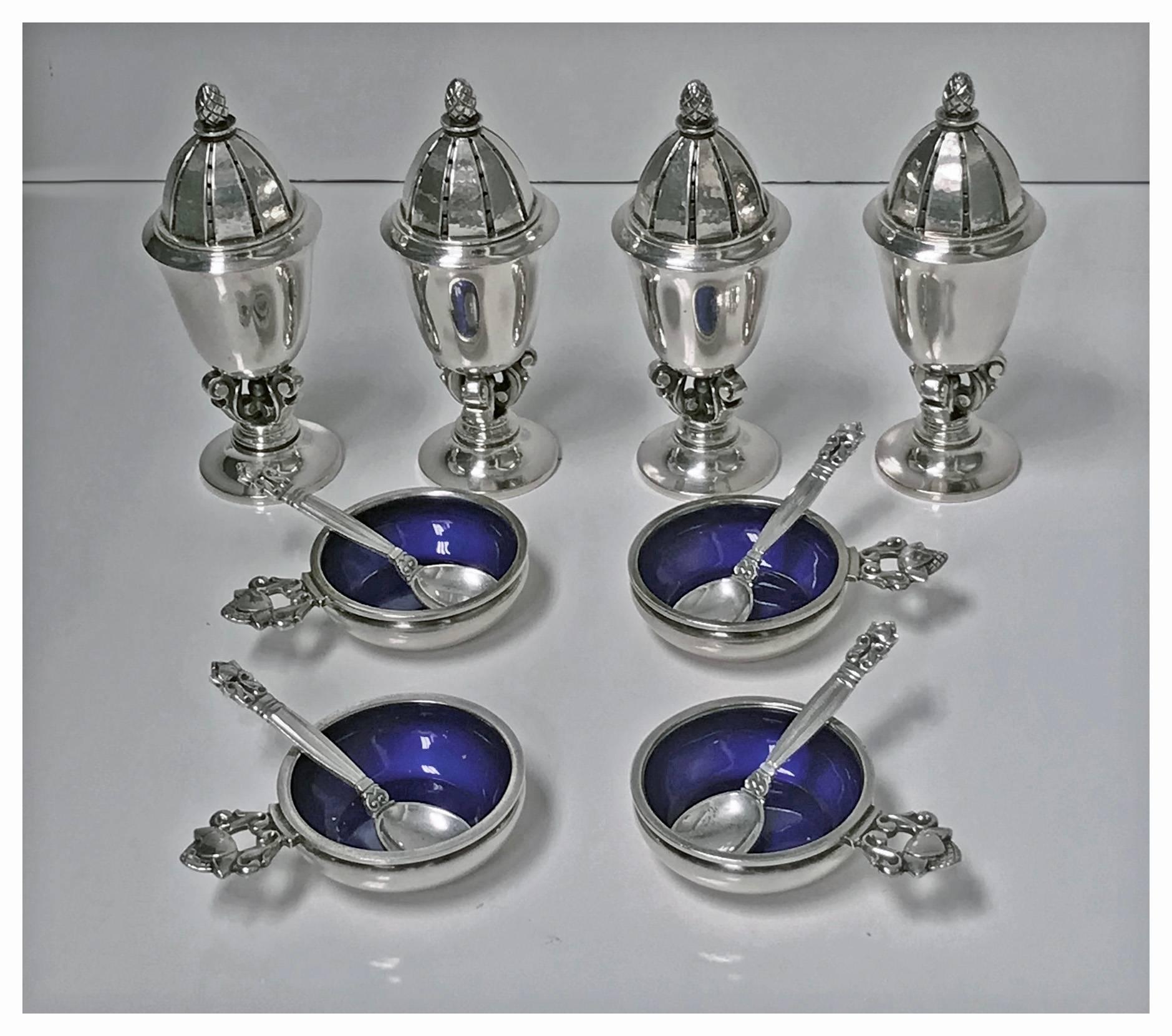 Four sets of Georg Jensen sterling salt dishes, pepper shakers and spoons, post-1945, no. 741, designed by Johan Rohde, acorn pattern. The casters urn form, with pineapple finials, vertically reeded lids, on trefoil openwork scroll base and small