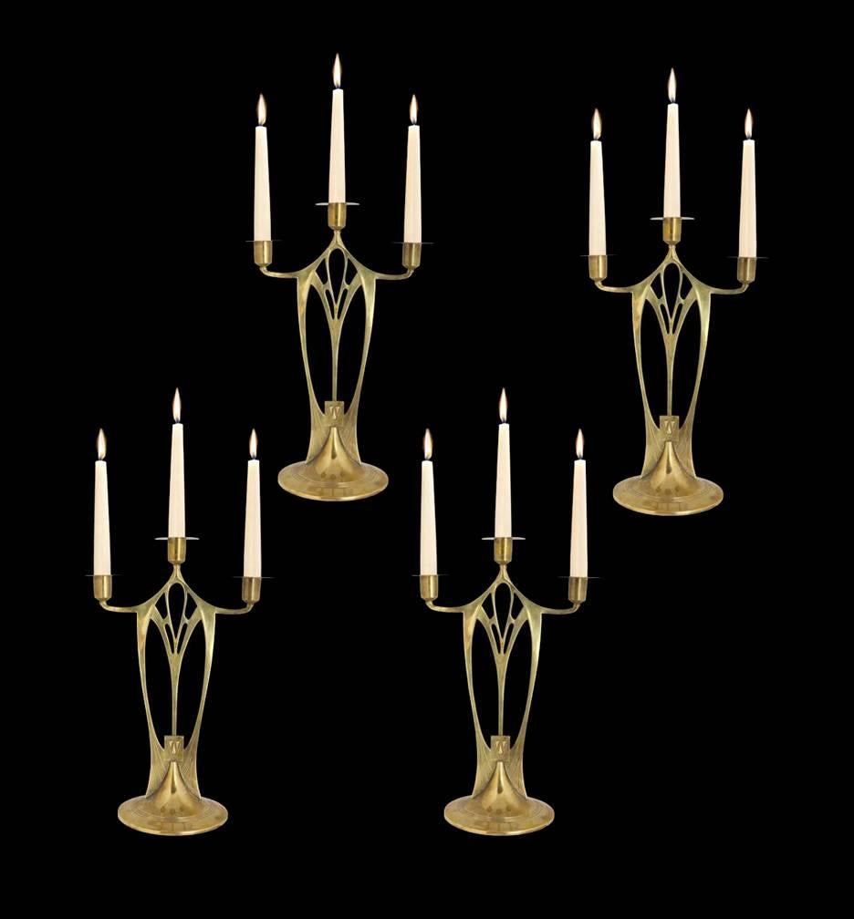 Set of four of WMF Jugendstil Secessionist Art Nouveau brass three-light candelabra, Germany, circa 1900. Each on circular base with ribbed surround, the body of an Egyptian Celtic motif open flat design, supporting three screw bobeche. Height: 14.5