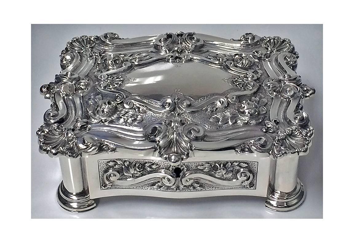 Antique silver casket jewellery box, rectangular shaped chest style body, stepped molded cornices, the body with panels of hand-chased floral decoration, hinged lid richly decorated with scroll, foliage and rosette centering vacant lozenge