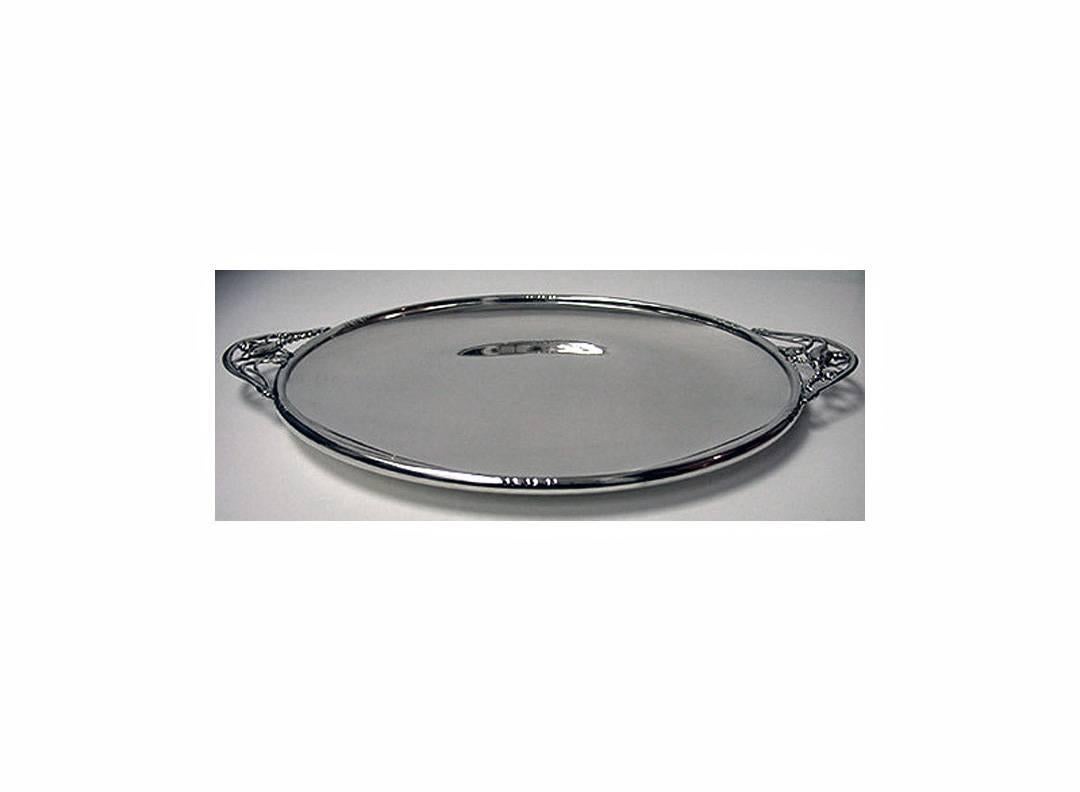 Sterling silver tray, C.1930. The tray of circular form, plain welled interior, the border and handles of Jensen style blossom leaf decoration. Stamped on underside Sterling H 112. Length: Approximately 15.25 inches (handle to handle). Weight: 21.5