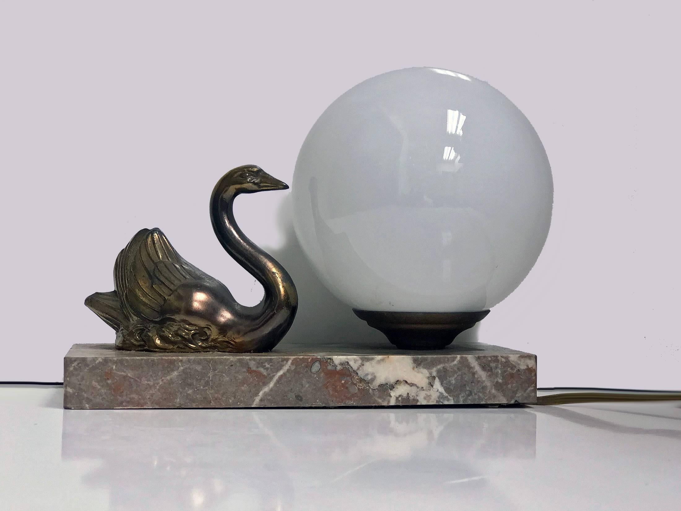French Art Deco swan lamp, circa 1930. The lamp with a spelter sculpture of Swan on marble base with tones of orange, brown and white, milk glass spherical lamp shade. Measures: Approximately 7.75 x 3.2 x 6.0 inches.
