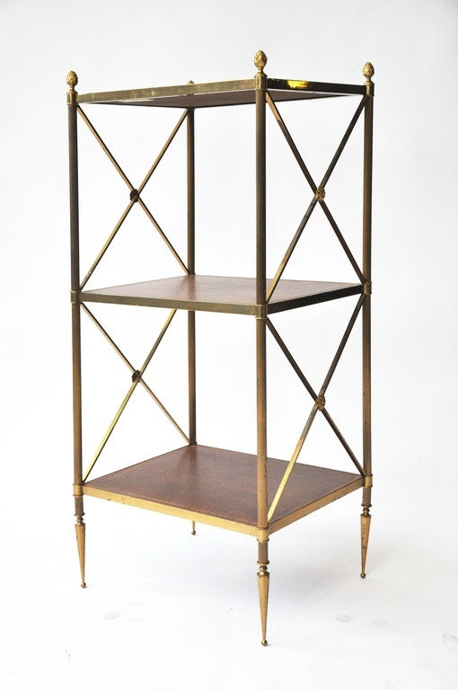 Elegant French brass 3-shelf étagère with leather shelves. Hand-painted gold leaf borders on each leather shelf in Greek key motif. Brass foliate capitals and floral decorations on sides. 