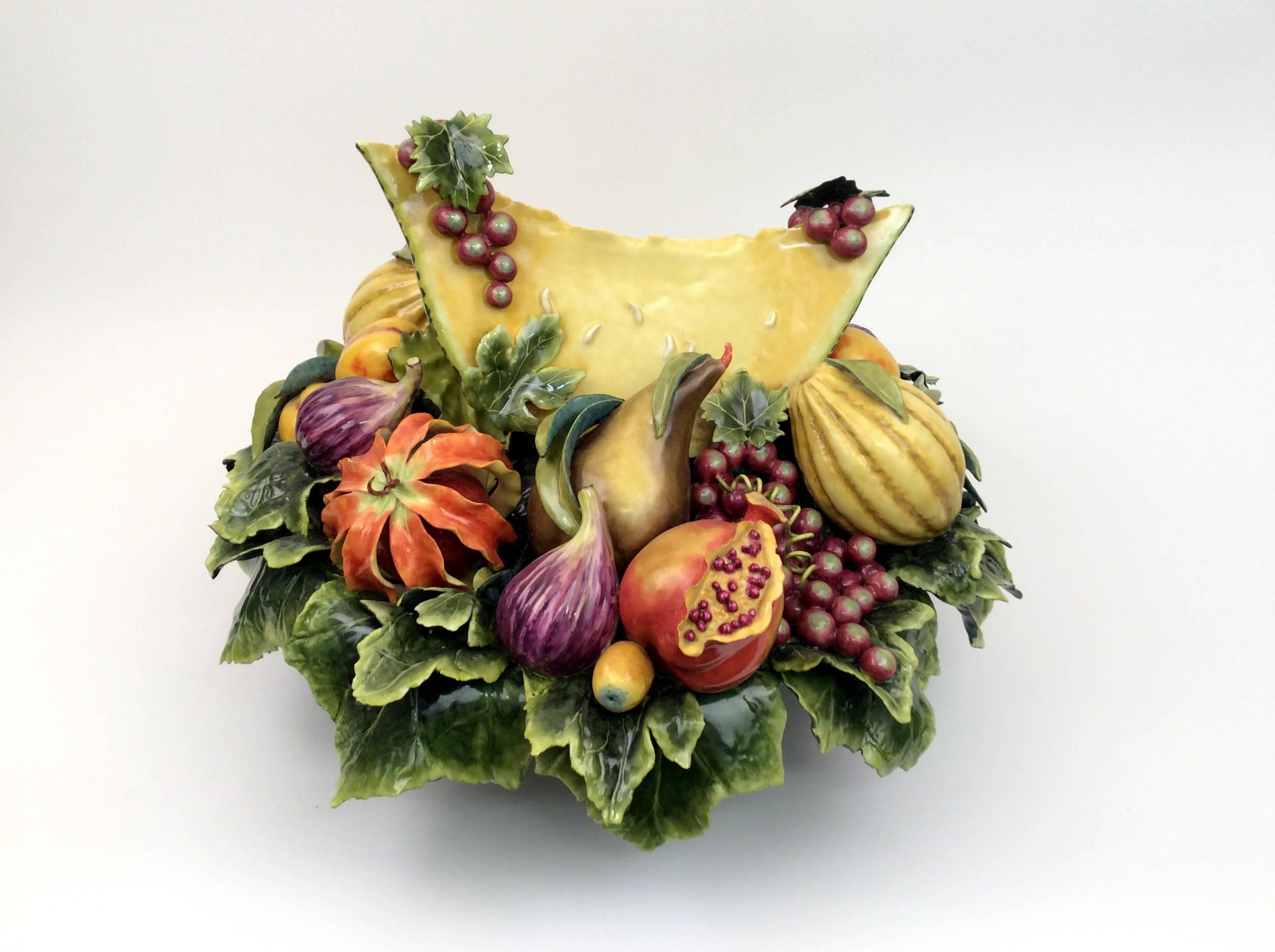 This large fruit bowl comes elevated on its own pedestal of leaves featuring a large melon wedge in the center of an arrangement of brightly colored fruits and grapes.
Katherine Houston is a living artist working in an 18th century technique,