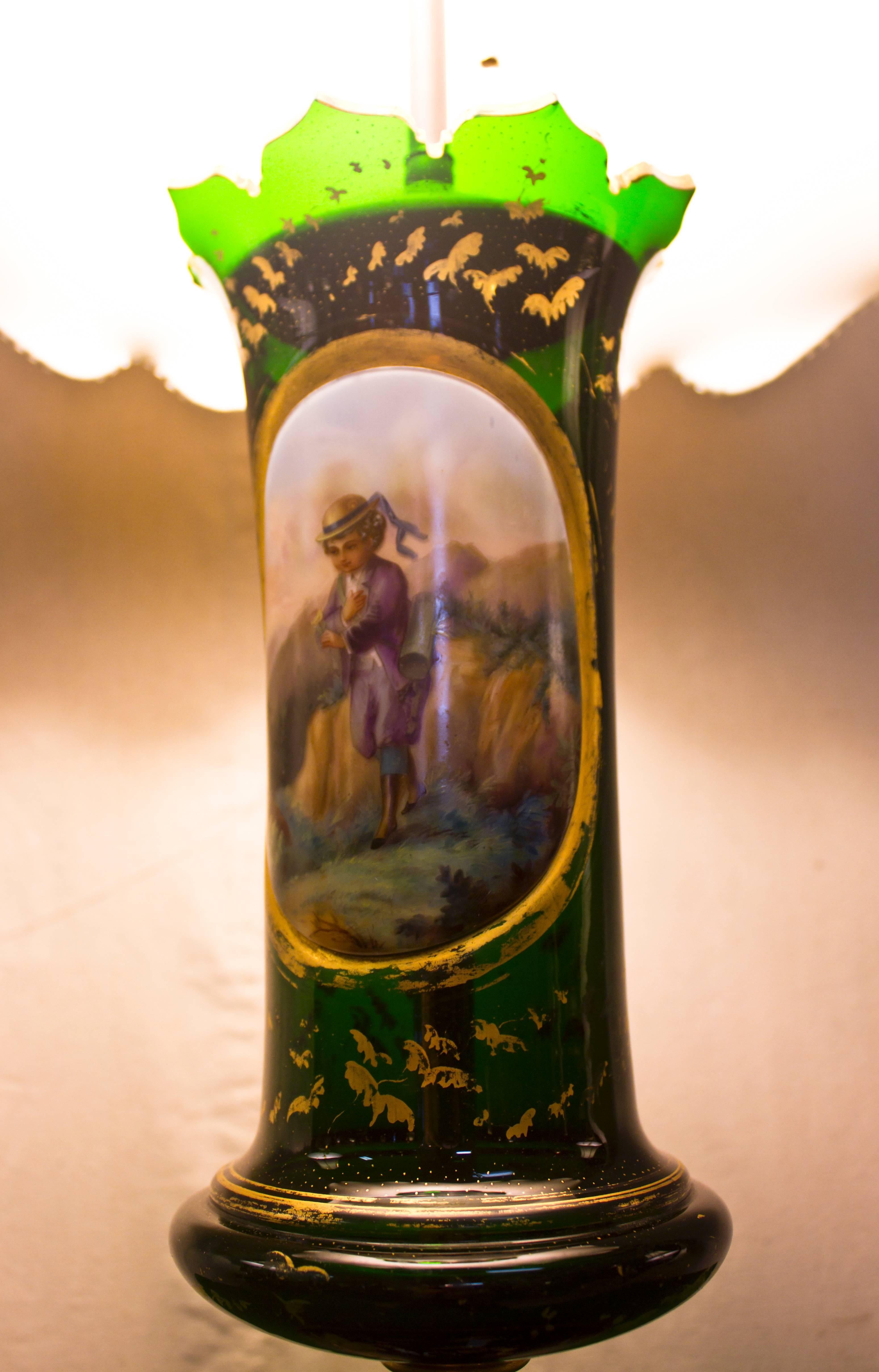 Austrian clear green glass vase converted into a handsome lamp. Featuring a scalloped top with a hand-painted scene of a little boy carrying a vasculum and collecting flowers in an Alpine setting. Gold leafing is highlighted throughout the glass.
