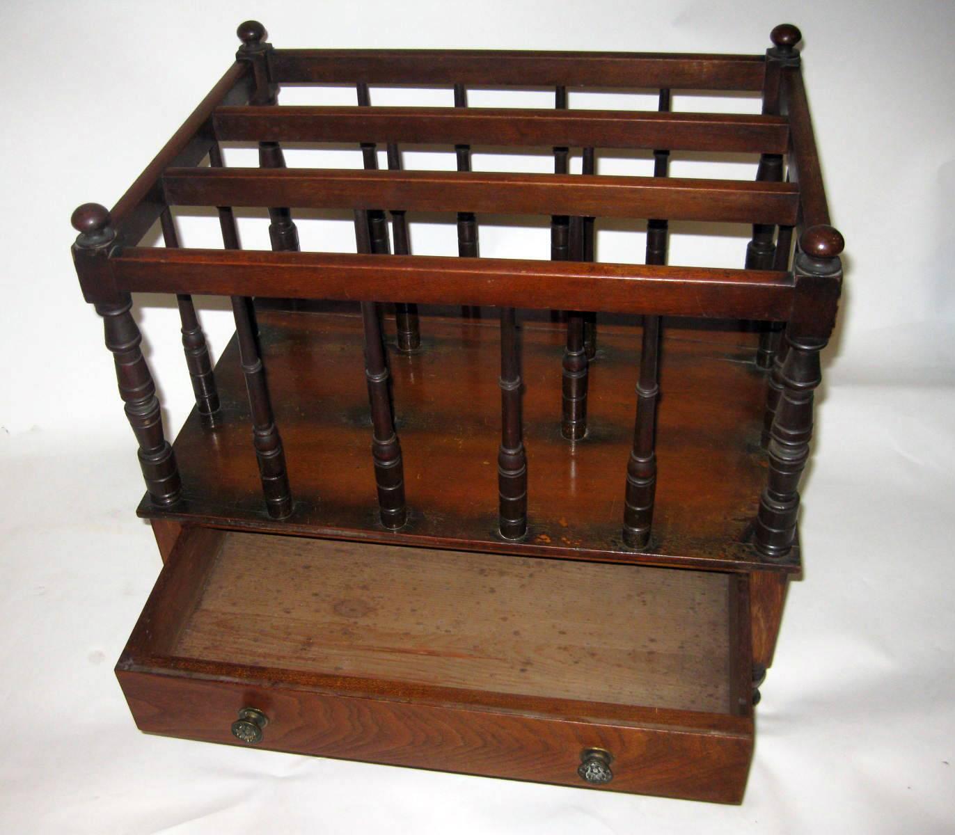 Regency period mahogany English Canterbury or magazine rack featuring turned supports, three sections and a single drawer with a secondary wood of pine on the bottom of the drawer. The fancy brass drawer pulls are original as are the brass casters