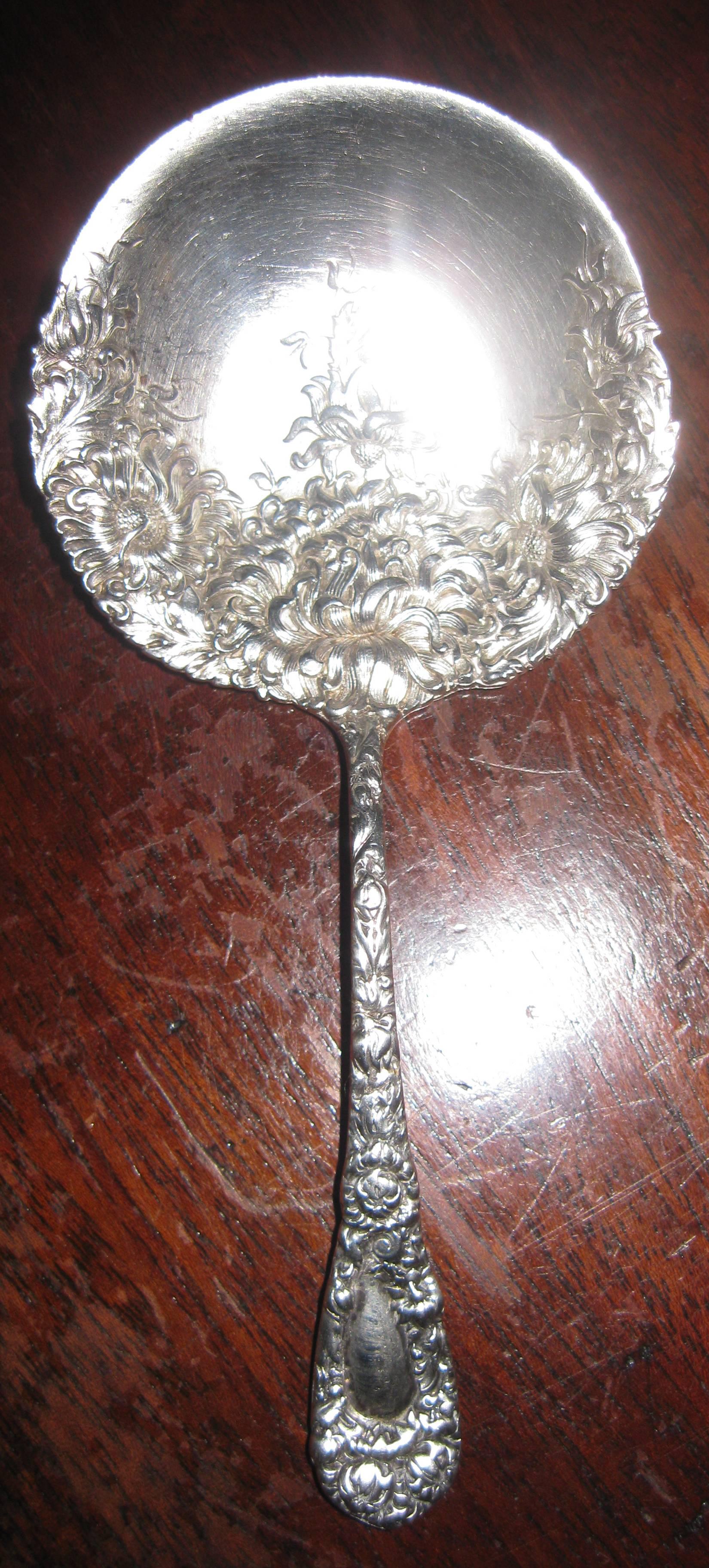 Sterling silver nut spoon made by the American company Durgin. It is in an intricate design in the chrysanthemum pattern introduced in 1893 and designed by George A. Muller. The piece is marked Sterling, 925/1000, B.B. &  B (the prestigious firm of