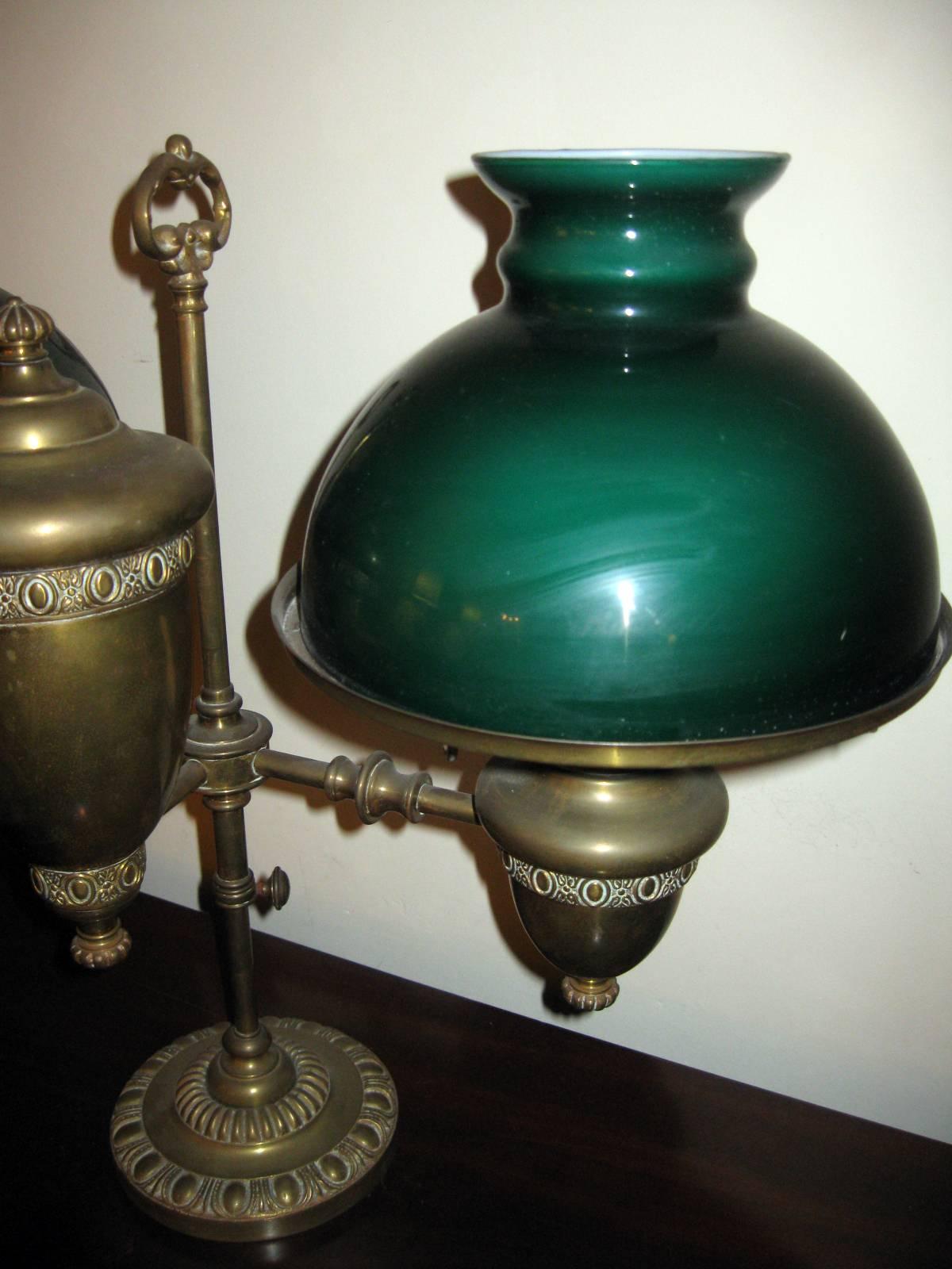 Double brass student kerosene burning oil lamp featuring an adjustable mechanism, double wicks and extinguishing levers that are marked Stern Bros. New York. We believe the double green shades to be original. Never electrified. The round base