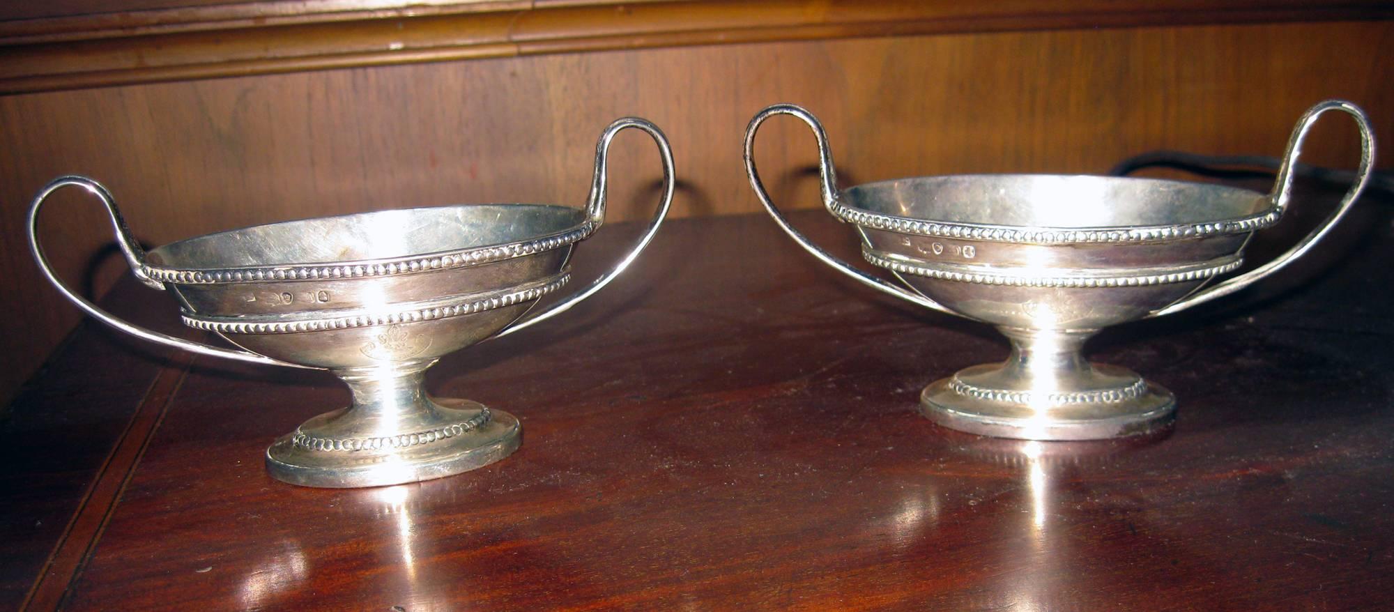Classic pair of Georgian sterling silver master salts with a graceful oval form and standing on plain oval spread foot. Each salt has a pair of reeded loop handles. The tops of the salts and the foot are embellished with a Classic bead pattern and