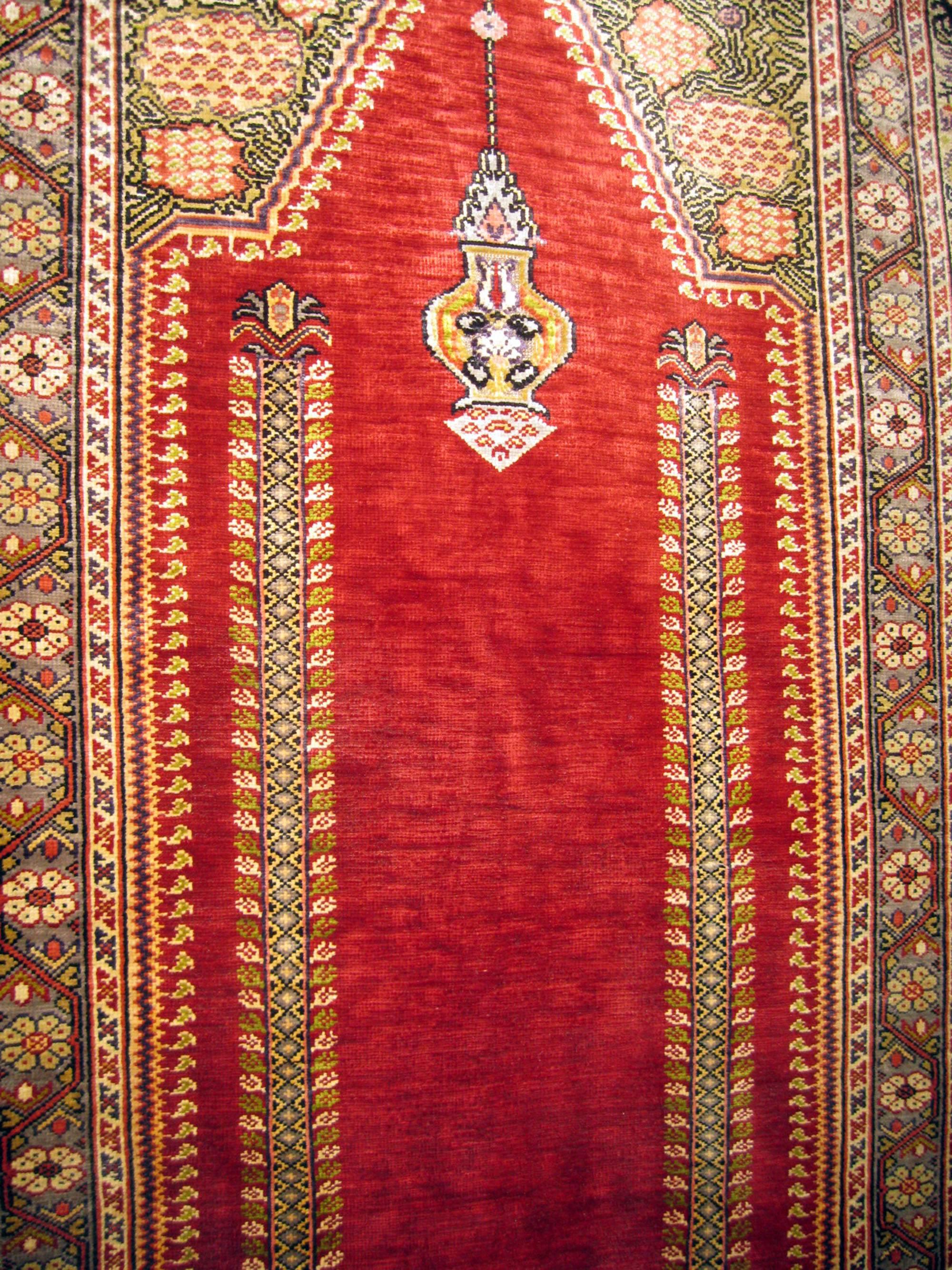 Ghiordes prayer rugs are among the most iconic of their type in Anatolia and the surrounding area. They traditionally feature angular prayer niches, highly decorative spandrels, architectural pillars and monochromatic fields. This Turkish silk