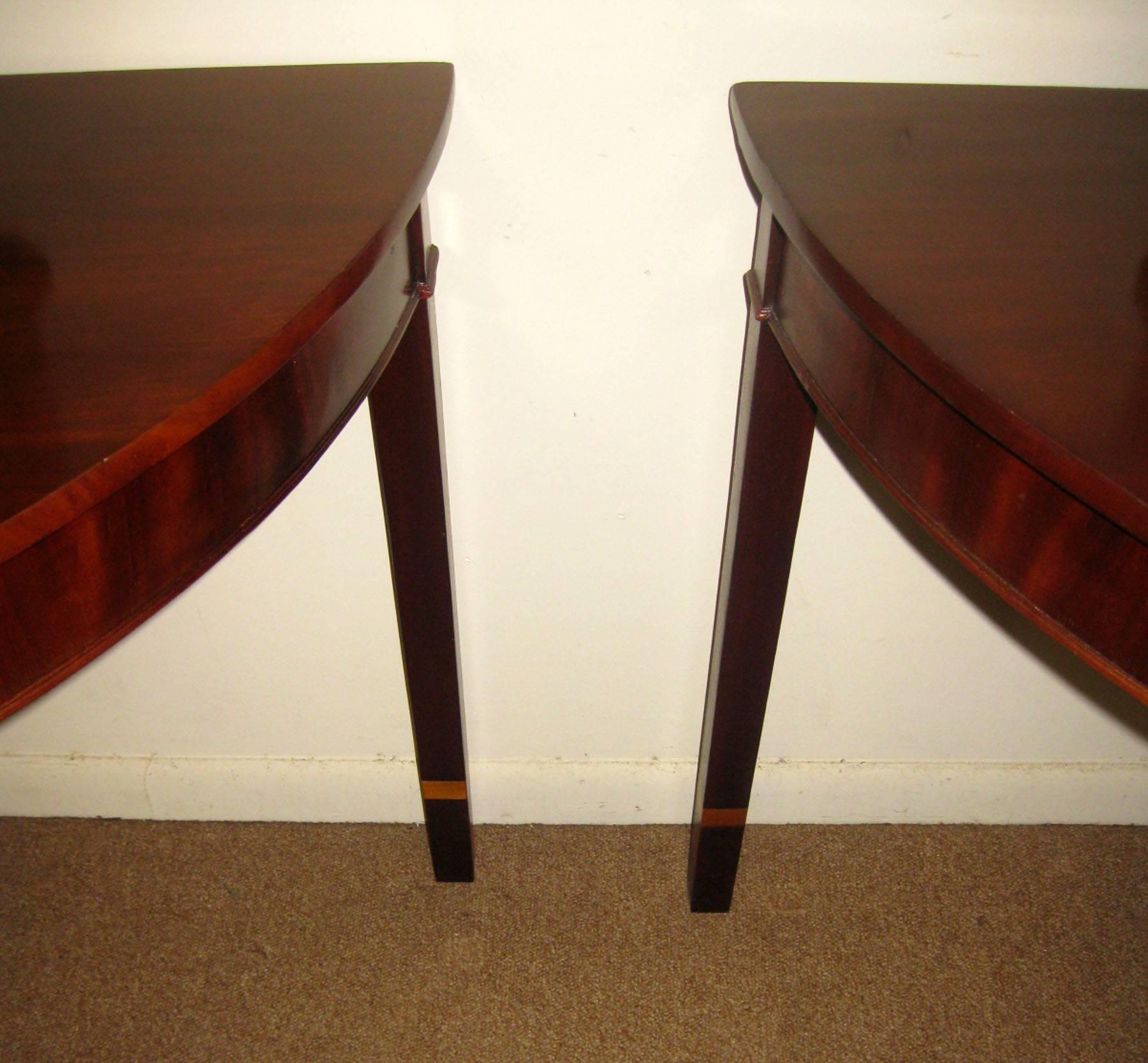 Handsome pair of English Hepplewhite style mahogany demi-lune console tables featuring four slightly tapered legs.
Large size. See measurements below.
