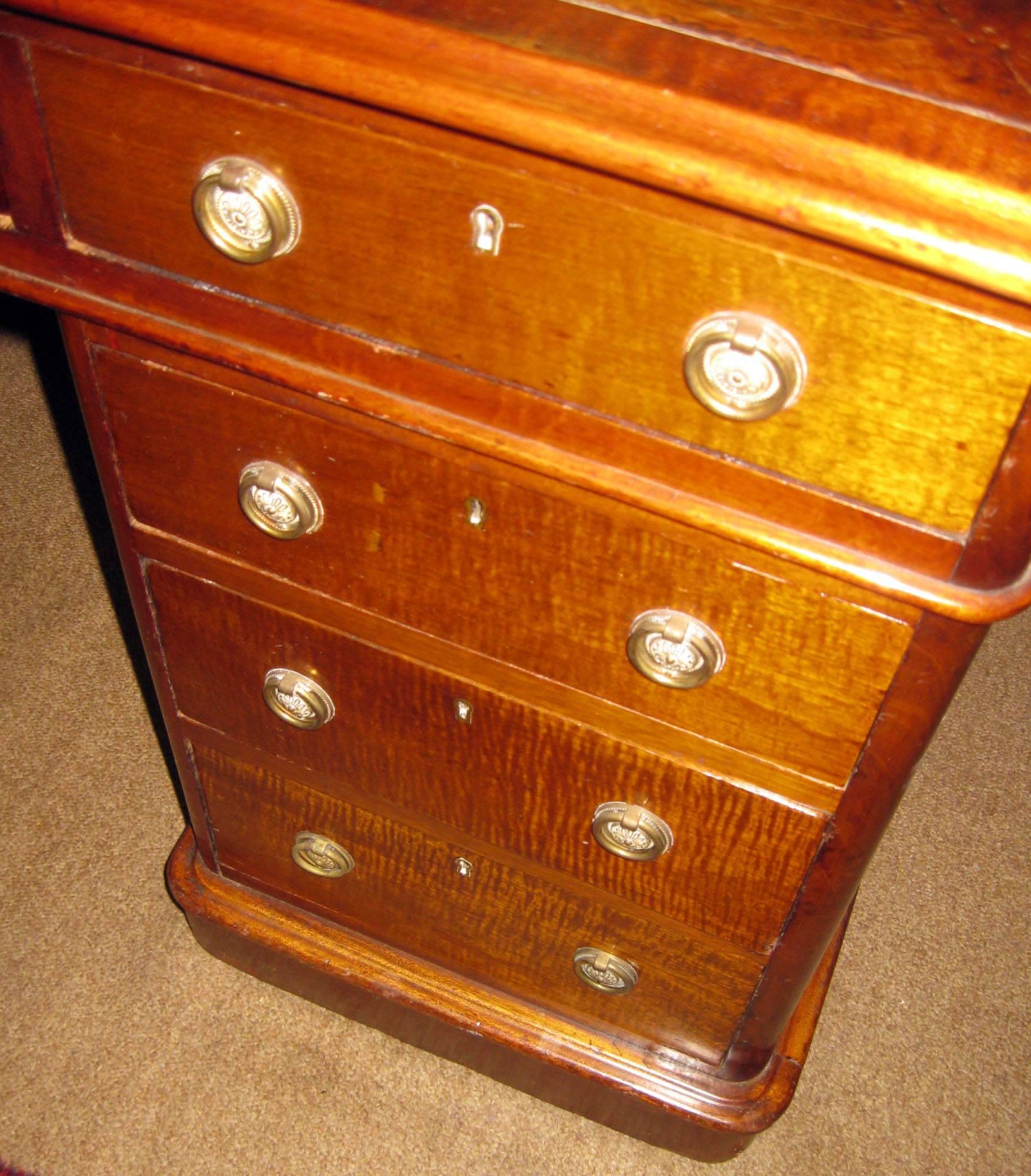 19th century large size English mahogany Regency period desk featuring an embossed leather top, brass pulls and side drawers. The back panel makes it possible for the desk to sit in the middle of a room and still look attractive. could be used as a