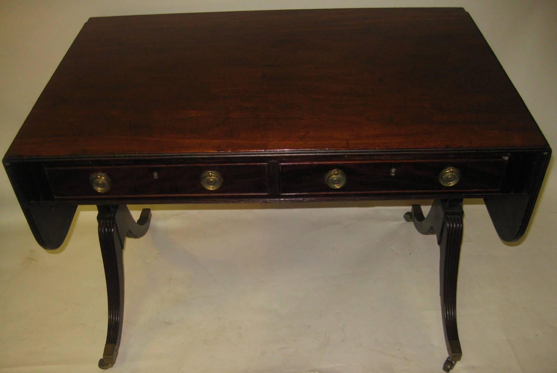 Handsome mahogany drop leaf sofa table with original finish and brass caps and casters. Two deep drawers with two false drawers in back. Reeded swept legs.
Measures: 60 inches wide when fully open. See other measurements below.