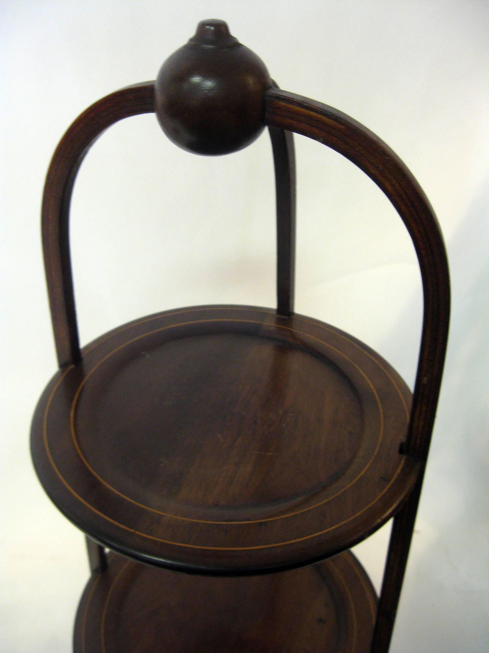 Mahogany muffin stand with three graduated sized shelves (Measures: 10 inches at top, 11 inches at middle, 12 inches at bottom) featuring string inlay and large sphere top ornament.