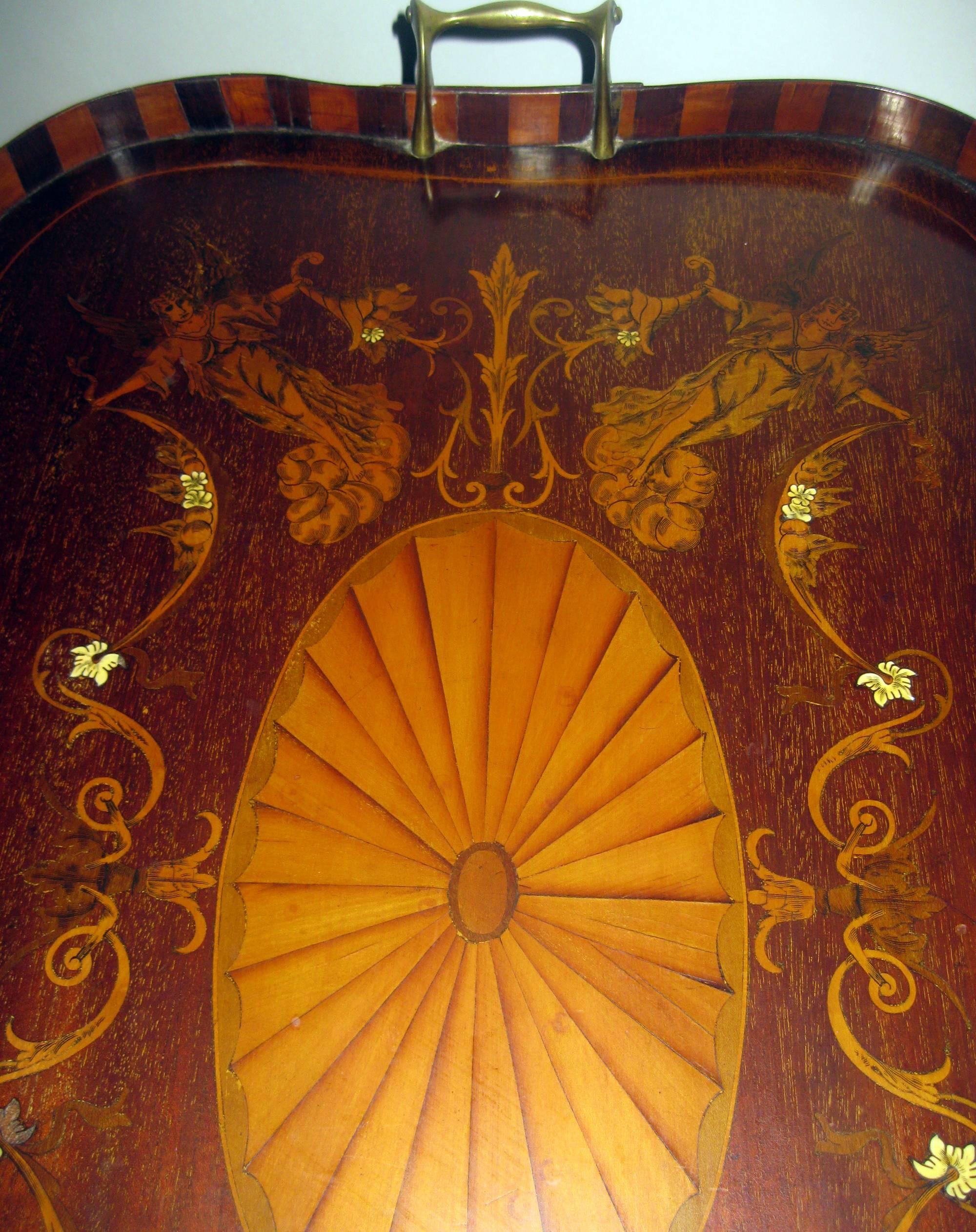 English mahogany Butler's tray with fanciful inlay and unusual curved wood gallery. Featuring four angels bearing cornucopias with scroll work around a center medallion and graceful brass handles, this fabulous one of a kind piece would make a