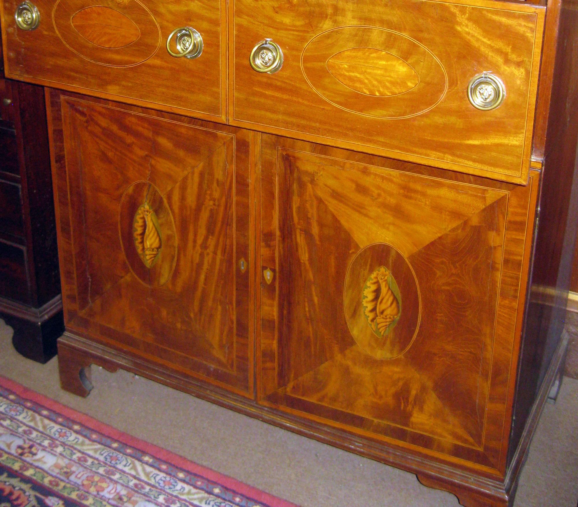 In a desirable light colored mahogany, this stately drop front butler's secretary features inlaid burled satinwood and fruit woods. The door veneers are quartered with a centre oval inlaid medallion and exquisitely done conch shell inlays on either