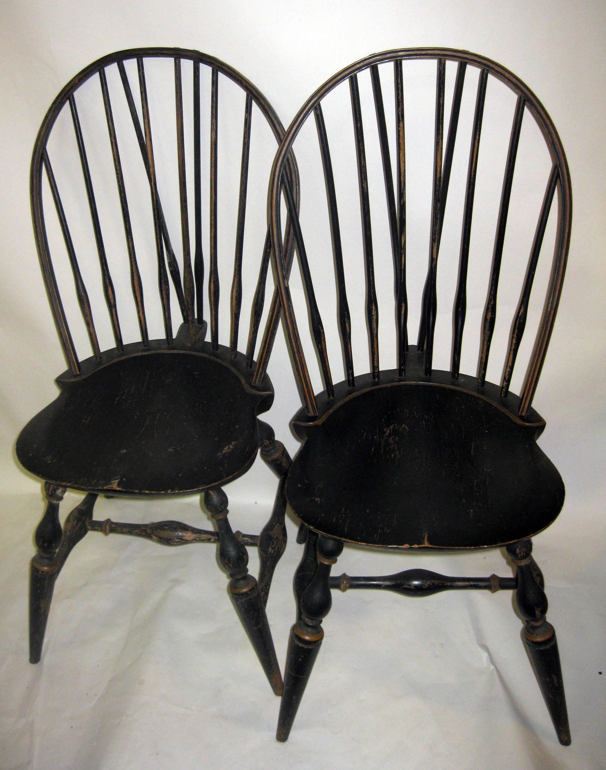 Eight bow backed American Windsor chairs with spindles braced by tail piece support. Distressed original painted surface with slight gold embellishment. These are typically made of multiple woods, in this case oak, maple and pine.