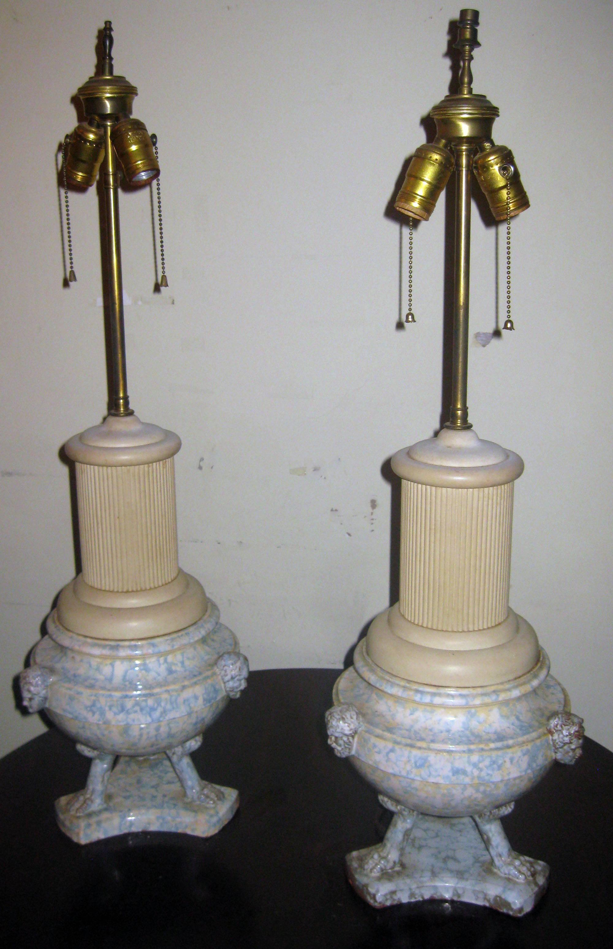 Pair of Italian blue and cream spongeware urns converted into table lamps with added earthenware columns. Features include tri animal feet bases and three different head figures at top of each urn. Double sockets. Urns themselves measure 9 .50