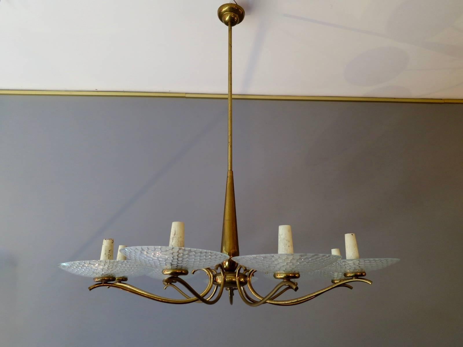 A 1950s Italian patinated brass eight-arm chandelier with large circular patterned glass diffusers. The candle style bulb holders slightly distressed.