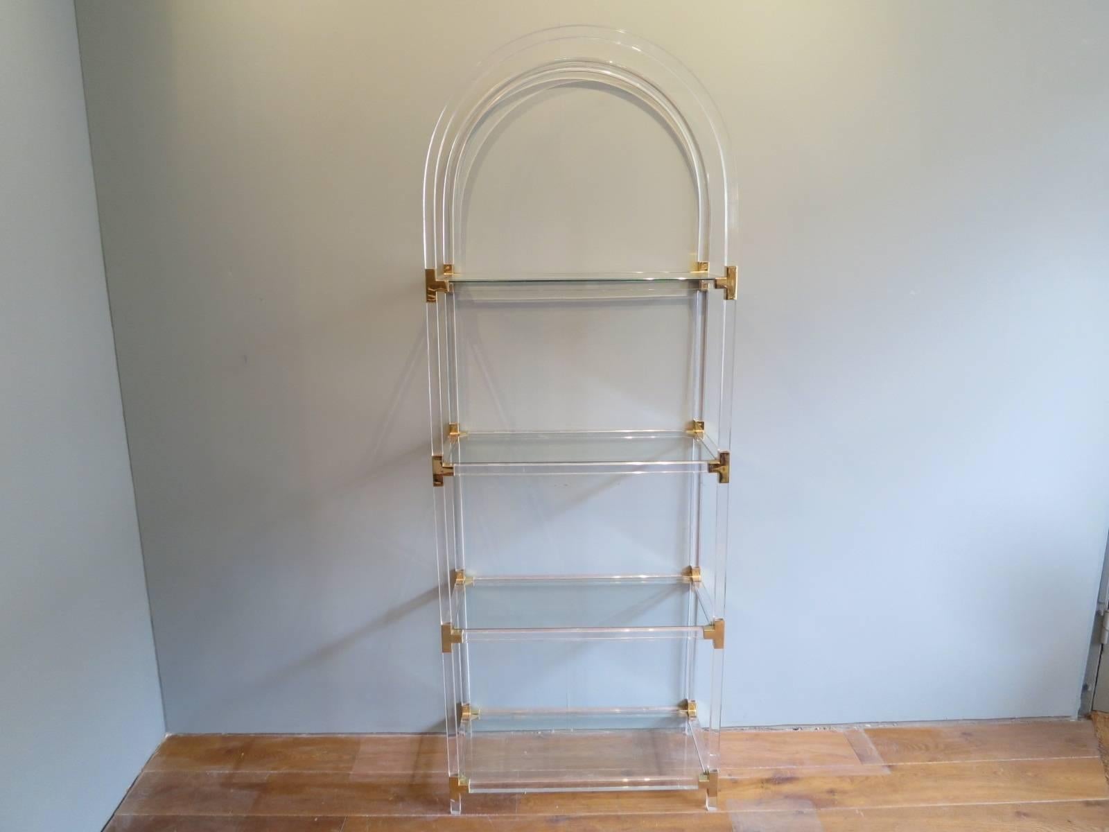 A tall domed top étagère on Lucite and brass with four glass shelfs, French, circa 1970s.