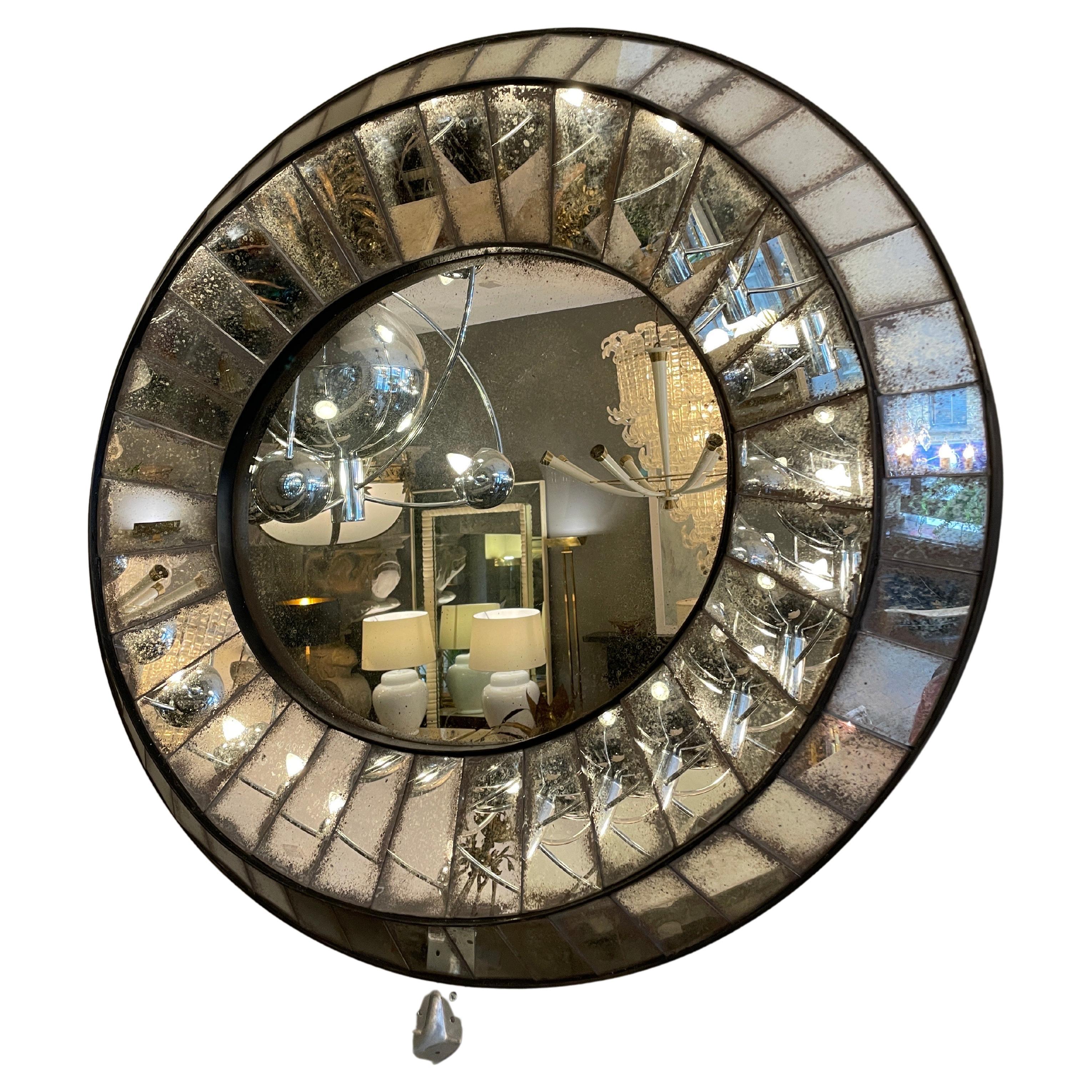 A large distressed oval shaped mirror with cushion panelled border. The faceted glass border heavily distressed with lighter distressed inner. Can be hung both portrait and landscape as seen in images. All glass within a black burnished steel frame.