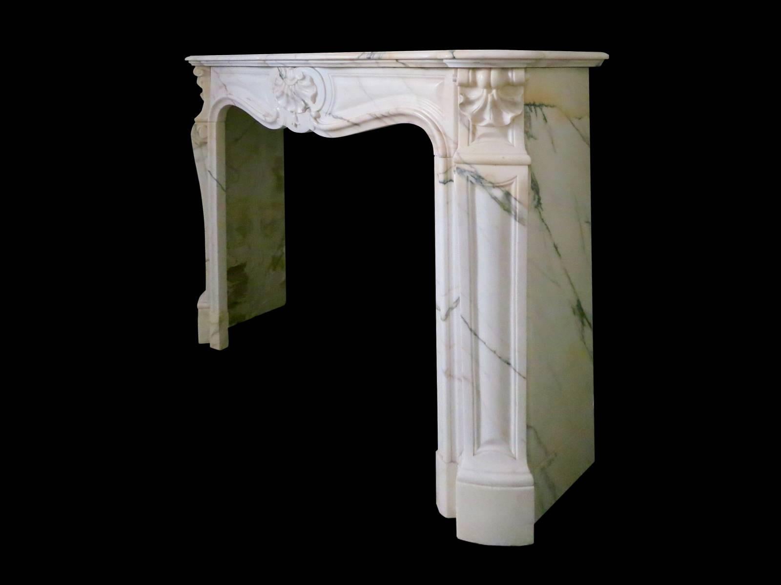 A compact Louis XV style fireplace in rare Italian Panazeau marble. The jambs surmounted by carved shells and scrolls. The panelled frieze with larger carved shell to centre, all beneath a serpentine moulded mantel.