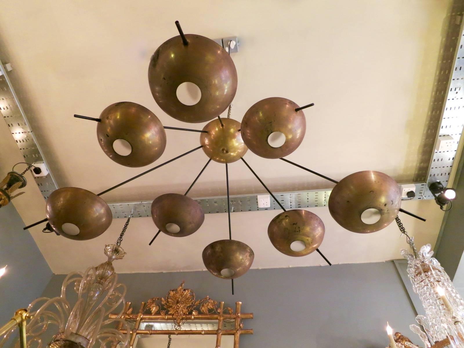 A large eight-arm Sputnik chandelier, with brass semicircular dish and opaque glass diffusers, with black powder coated arms. Brass showing patination and some distress (can be polished if required). Re-wired.
      
