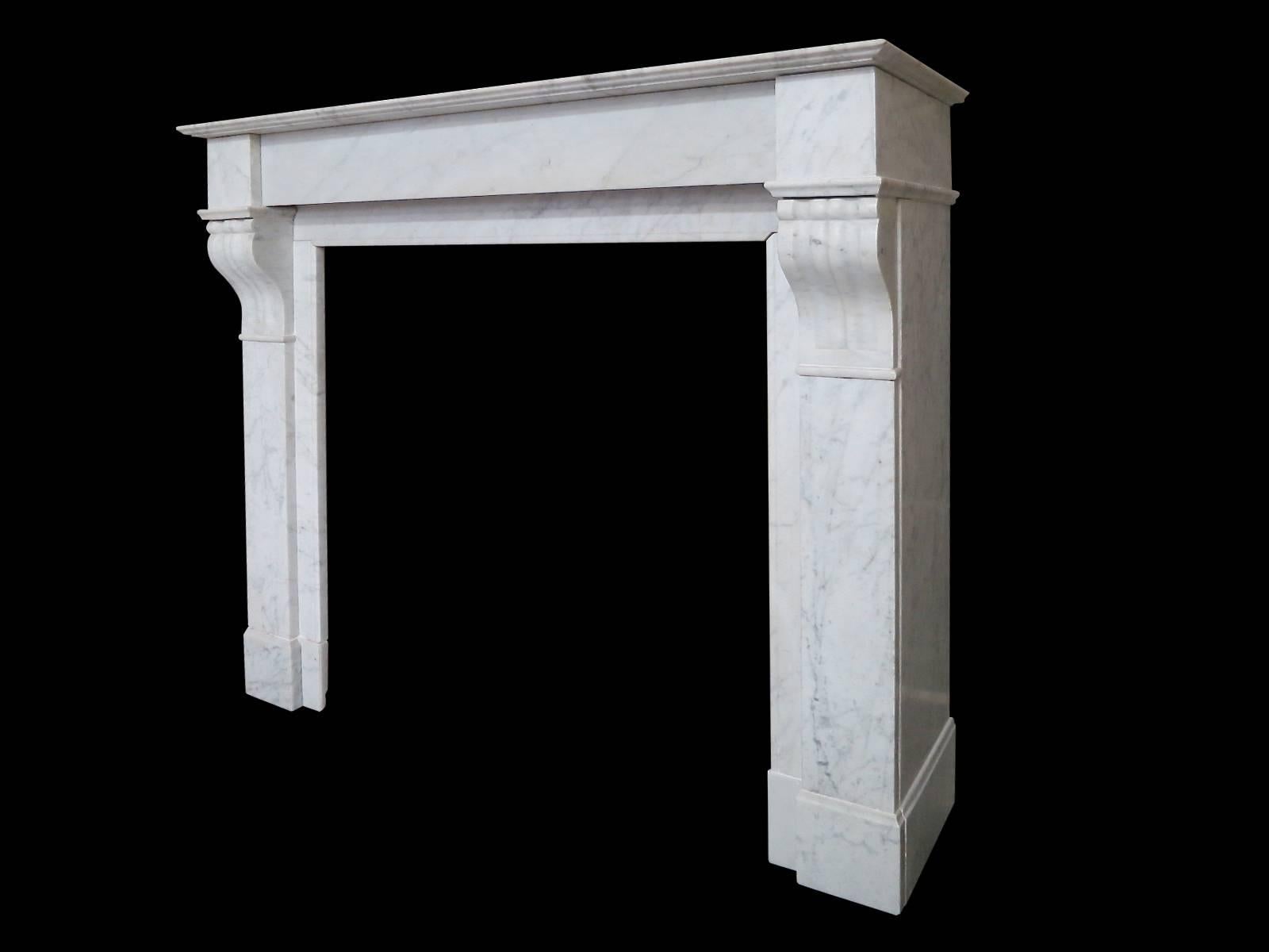 An antique French Louis XVI style fireplace in Italian Carrara marble. The plain jambs surmounted by carved corbels and plain end blocks, with a simple plain frieze and inner slips. All beneath a tiered mantel. Mid-19th century

Opening 76.5cm w x