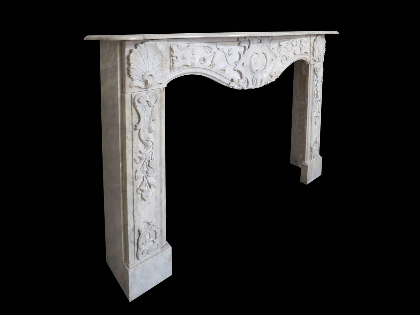 A very late 18th century Italian fireplace in Carrara marble, the deep serpentine shelf with profusely carved frieze below with large central cartouche, tendrils, vines and flowers. The end blocks of shells with descending foliage conforming with