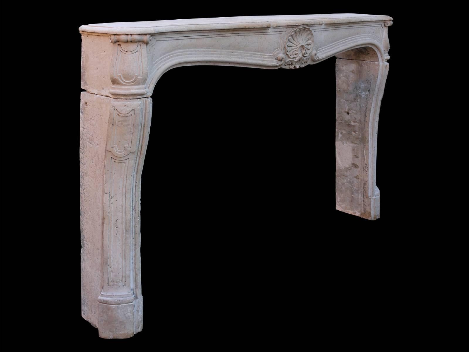 A large and well proportioned surround, carved in French limestone. The cantered and panelled jambs supporting a wide panelled prize with carved shell cartouche to centre, with conforming scrolled and panelled end blocks. All beneath a large