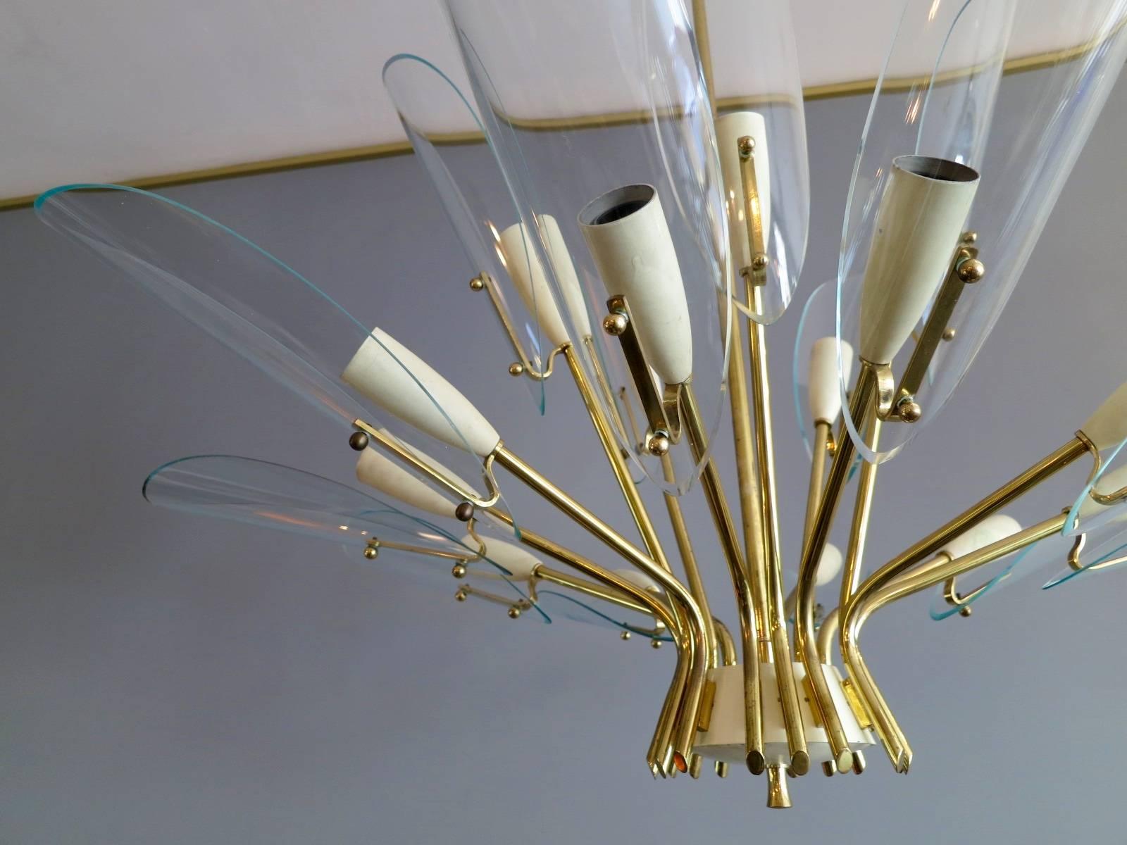 A very stylized 1950s chandelier in brass with ivory accents and large glass leaf shaped diffusers. There are fifteen-light fittings over two tiers. A well manufactured piece from one of Italy's finer production companies.