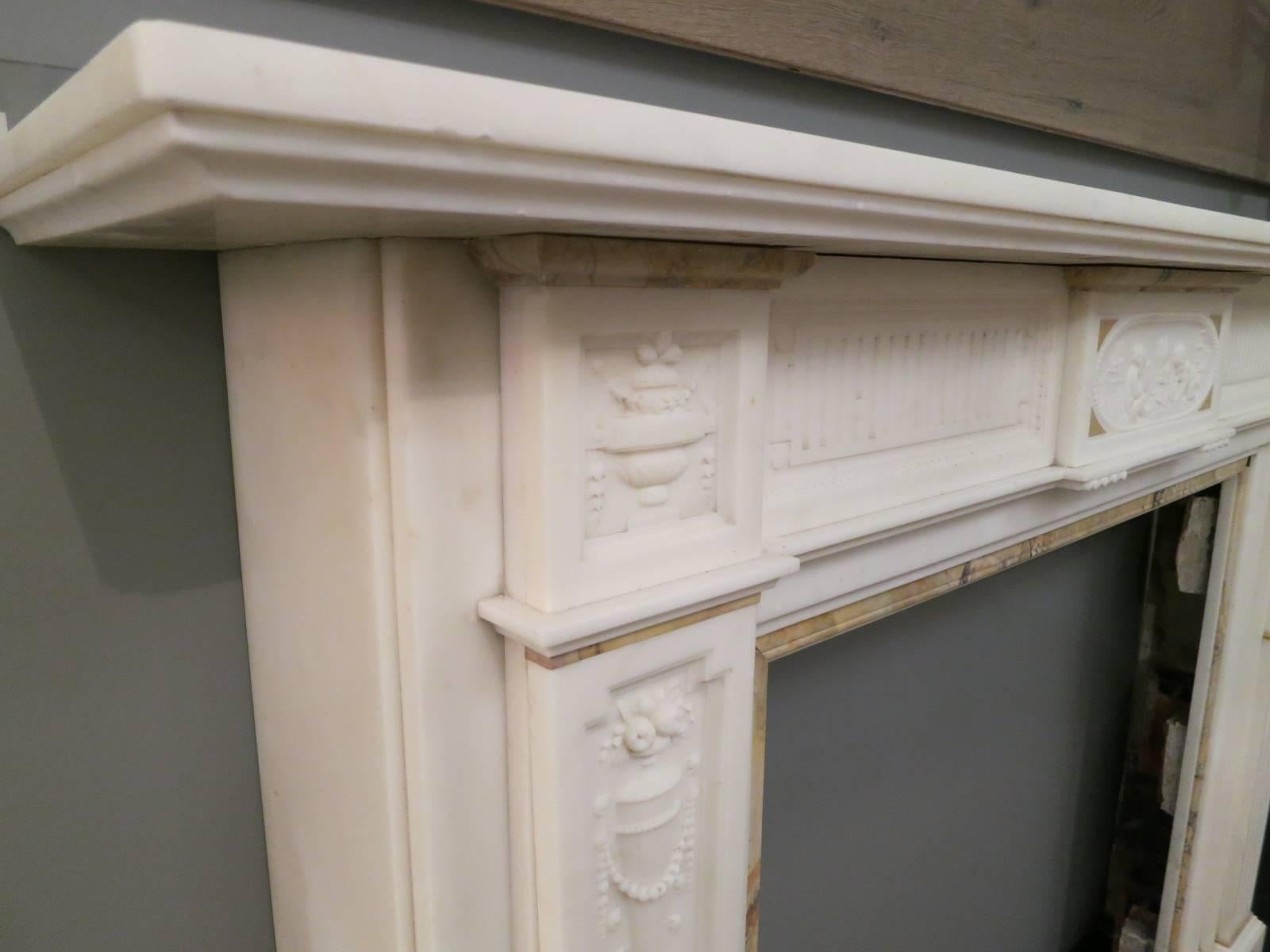 A quality late 19th century Regency style fireplace, executed in Italian statuary white marble, with Sienna marble inner slips, capitals and mouldings. The jambs having fluted panels with carved husks, separated by a Sienna marble moulding with